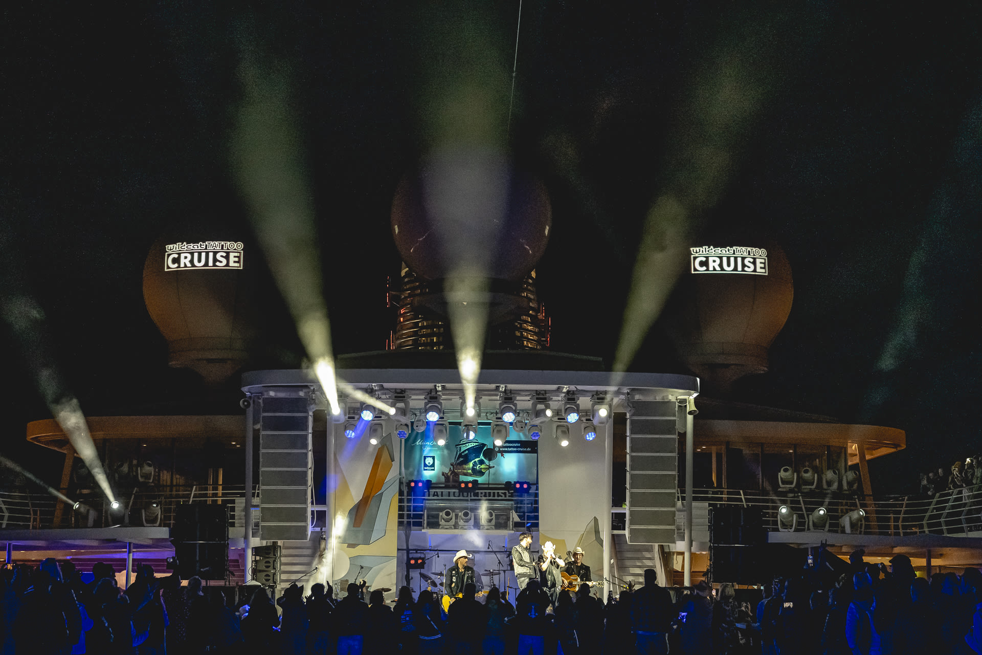 Nachtkonzert auf Kreuzfahrtschiff mit Lichtern und Publikum.