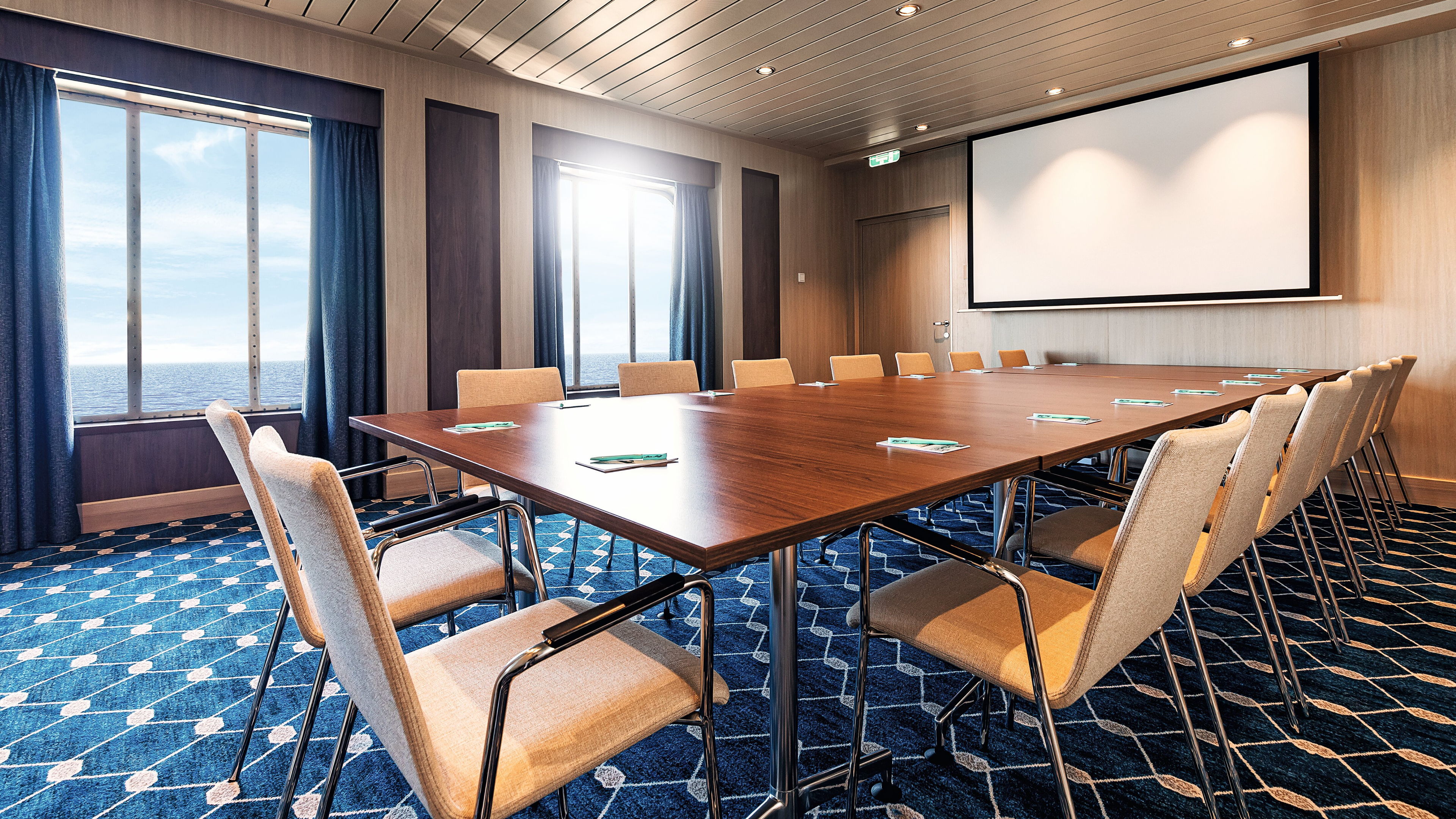 Konferenzraum mit großem Holztisch, Stühlen, Fensterblick auf das Meer, Leinwand.