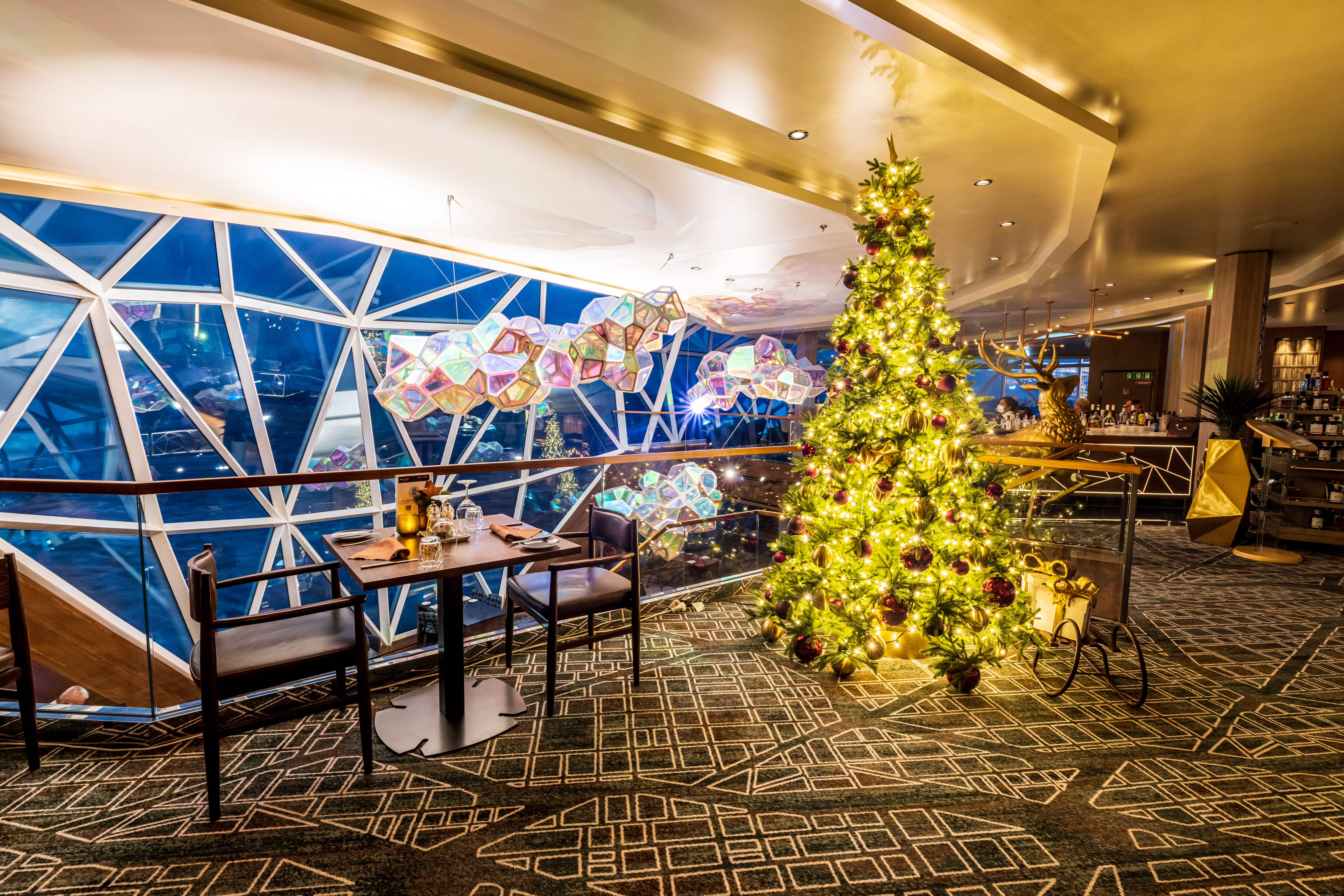 Weihnachtsbaum im Restaurant, festlich dekoriert, mit Lichtern und Geschenken.