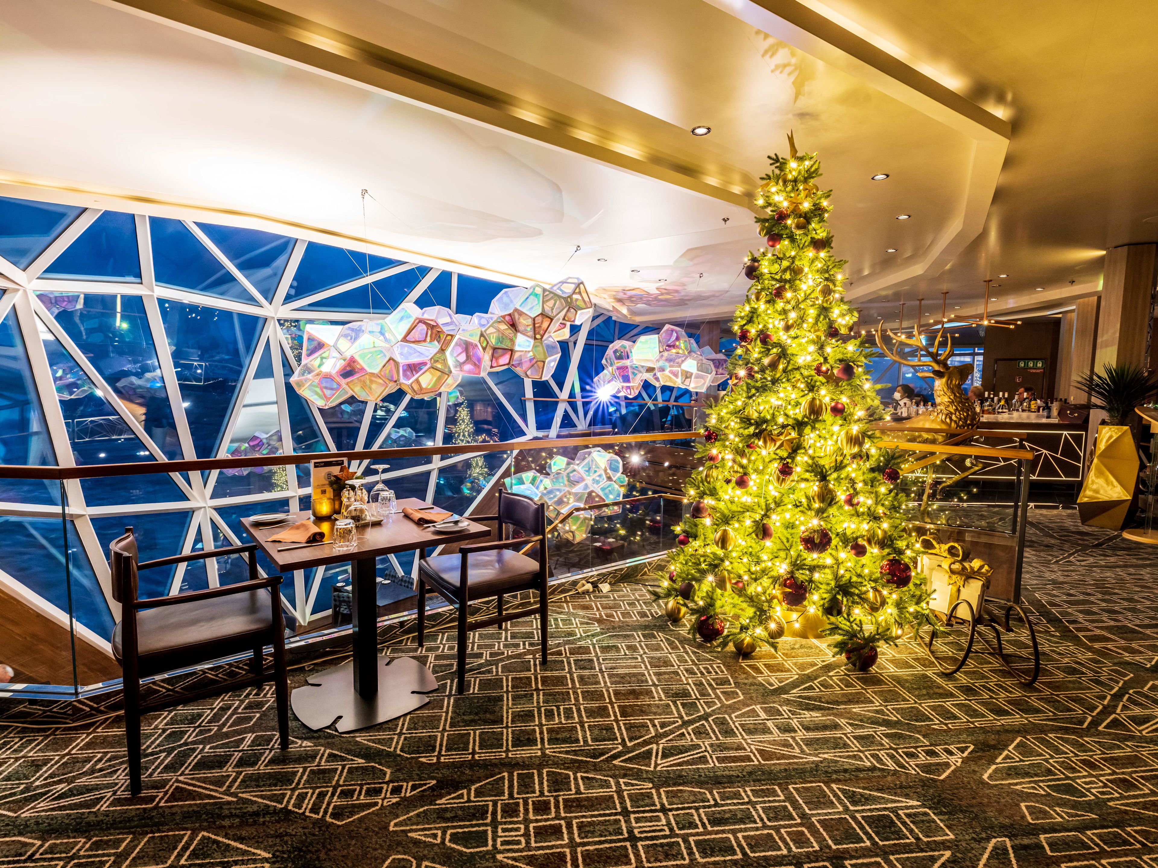 Weihnachten an Bord Weihnachtsbaum im Restaurant, festlich dekoriert, mit Lichtern und Geschenken.