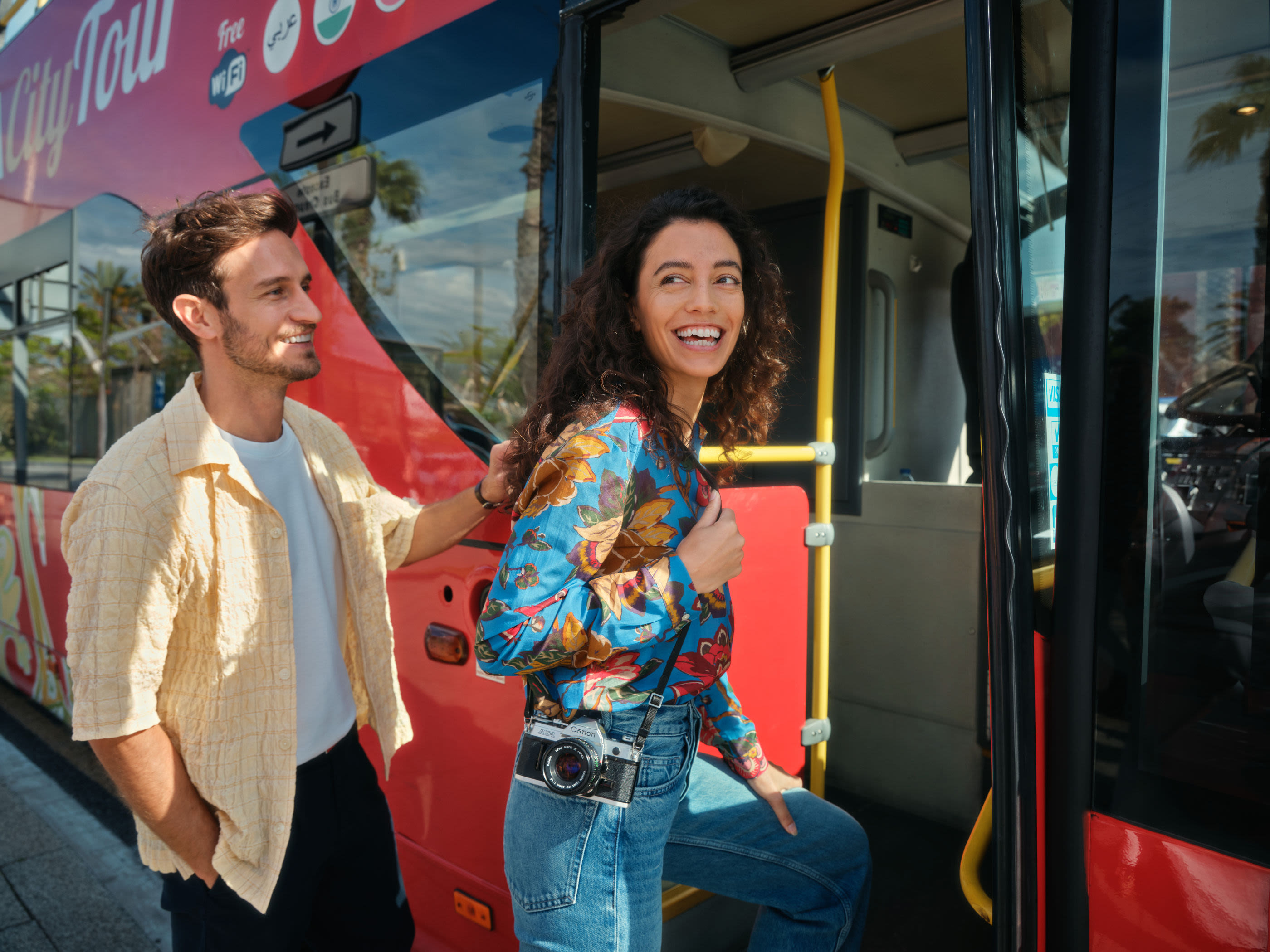 Paar steigt in roten Sightseeing-Bus ein, lächelnd.