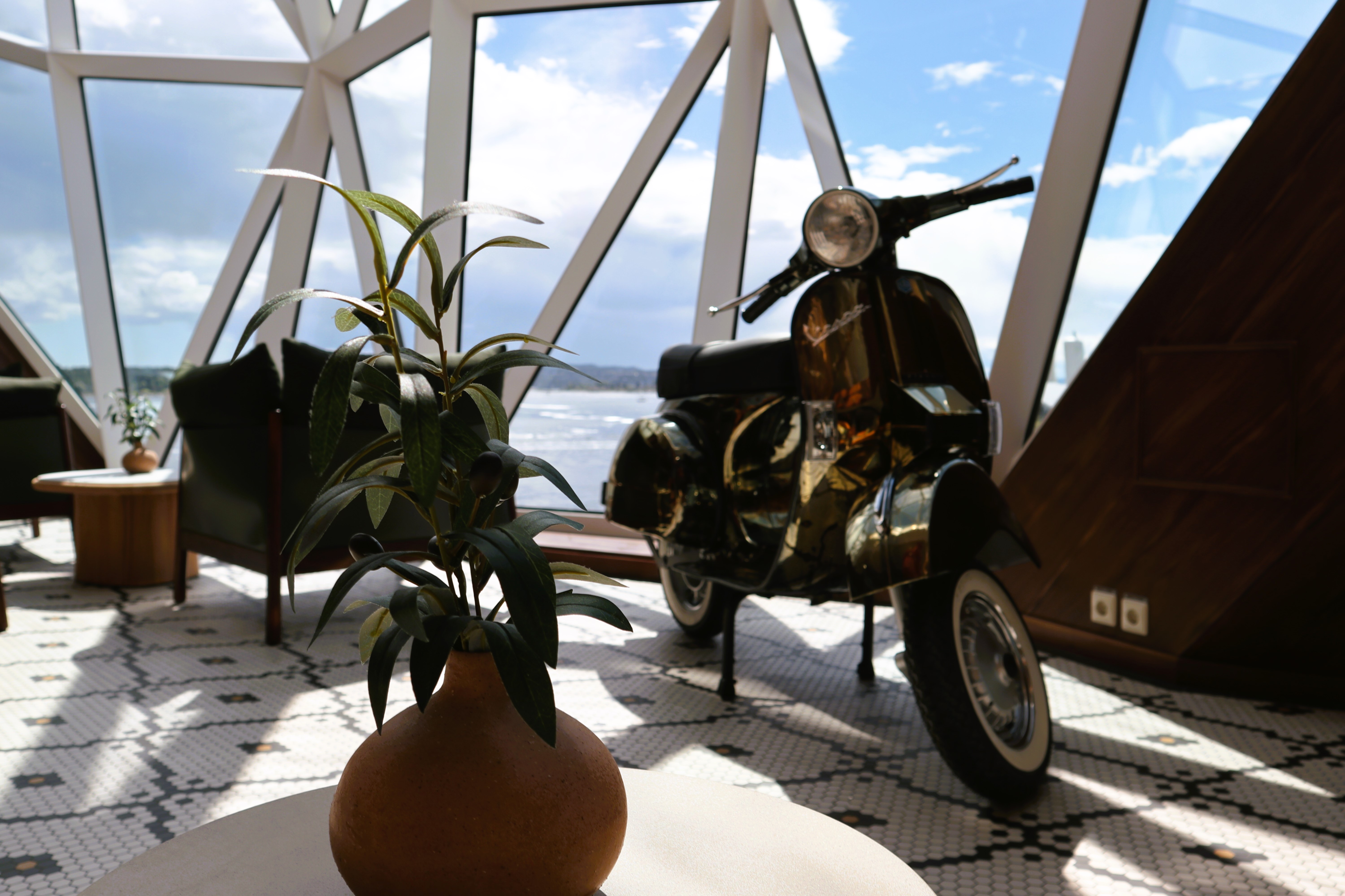 Pflanze und Vespa in modernem Raum mit Meerblick.