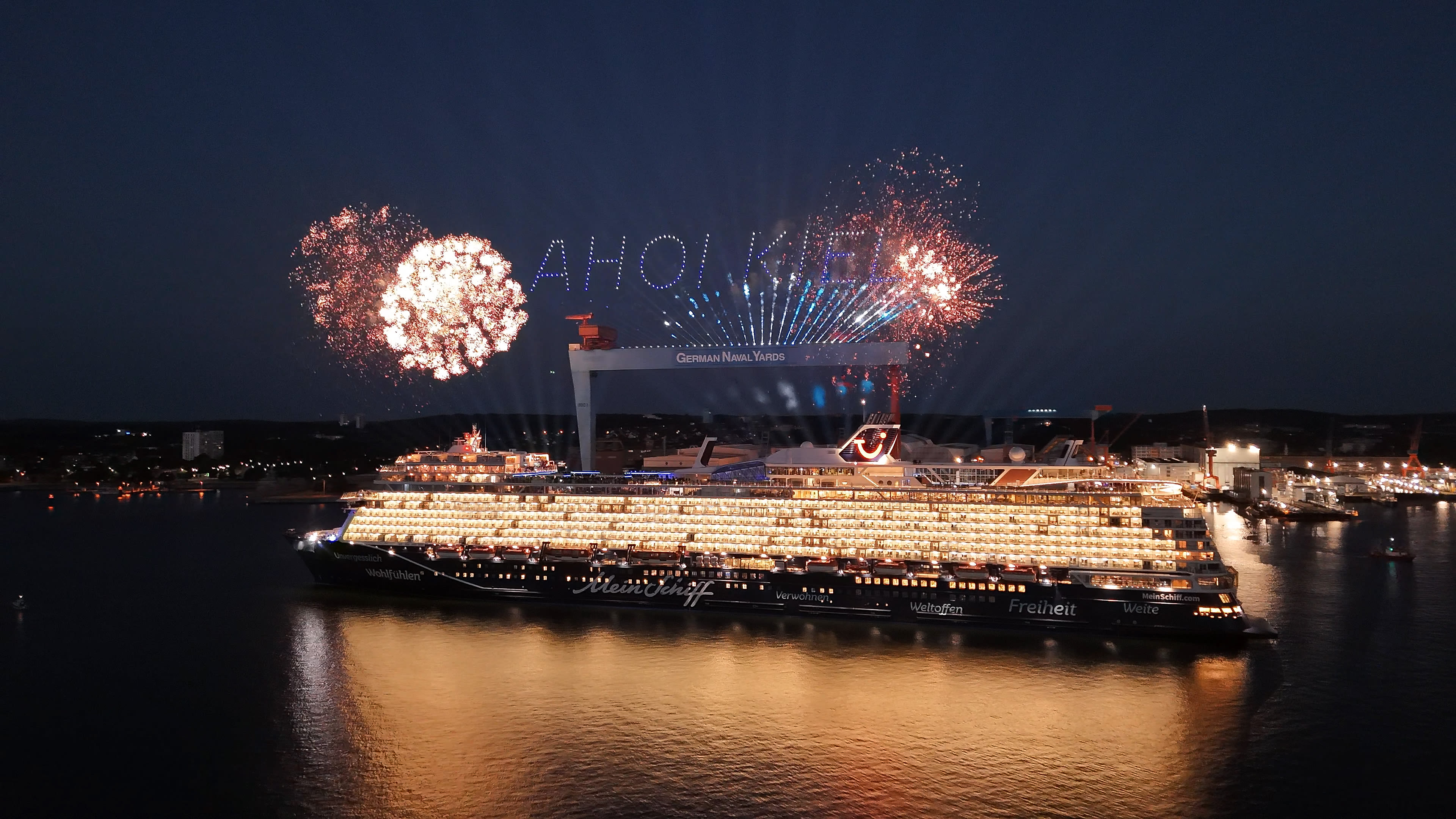 Kreuzfahrtschiff der Mein Schiff® Flotte bei Nacht mit Feuerwerk in Kiel.