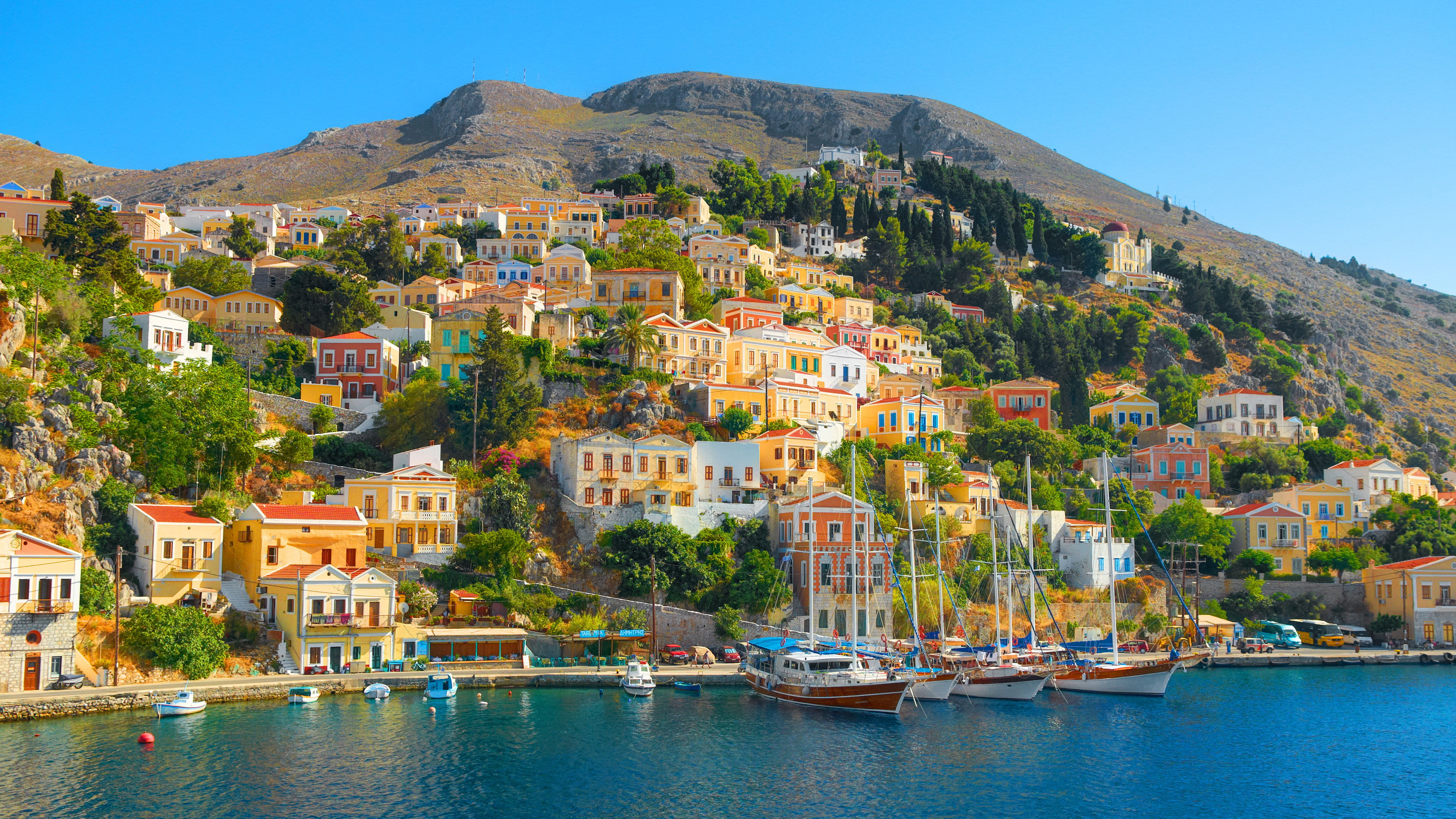 Östliches Mittelmeer - Griechenland - Shutterstock Bunte Häuser auf Symi, Griechenland, am Hang mit Segelbooten im Hafen.