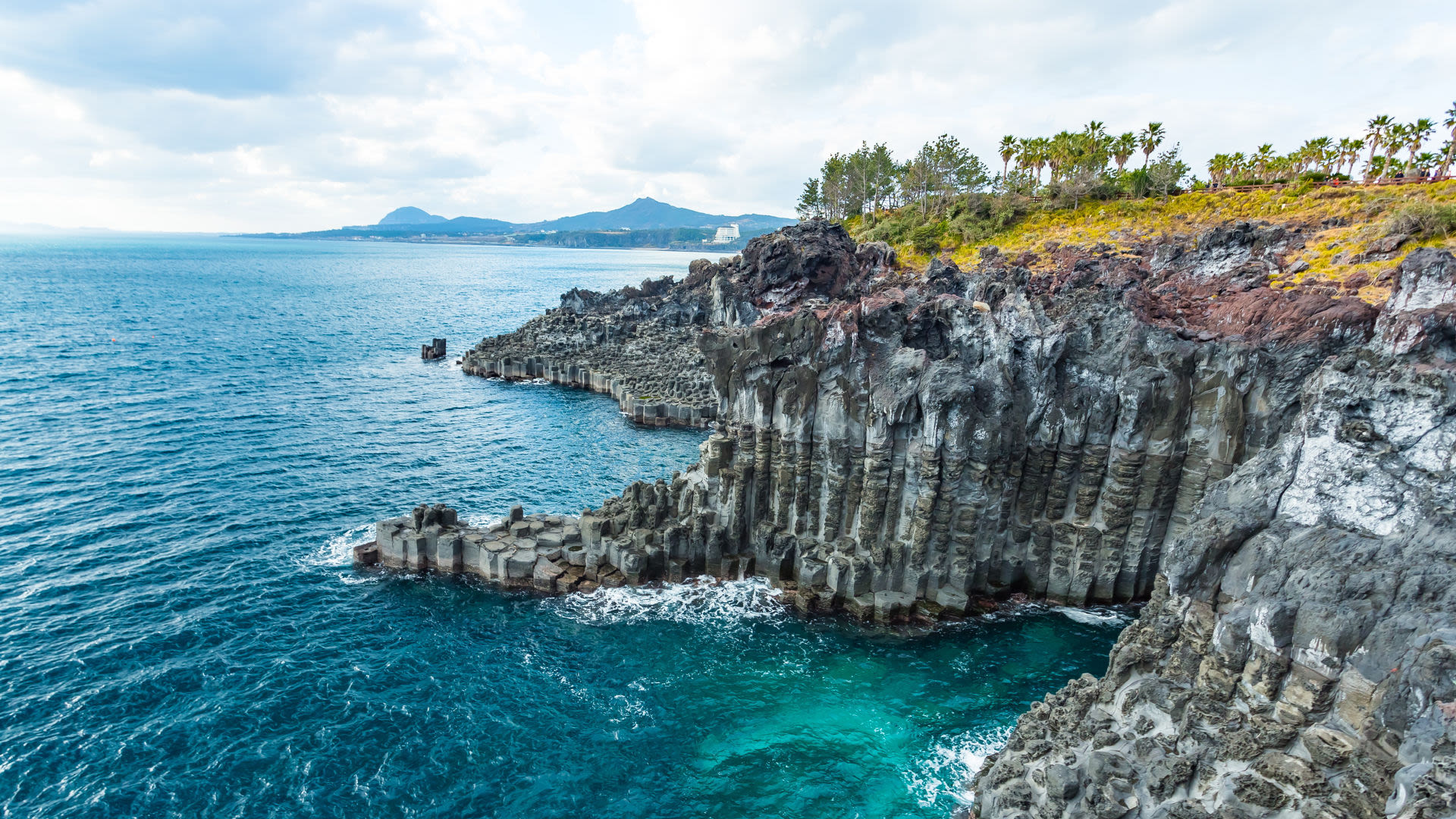 Küstenlinie mit Basaltfelsen und blauem Meer auf Jeju-Insel.