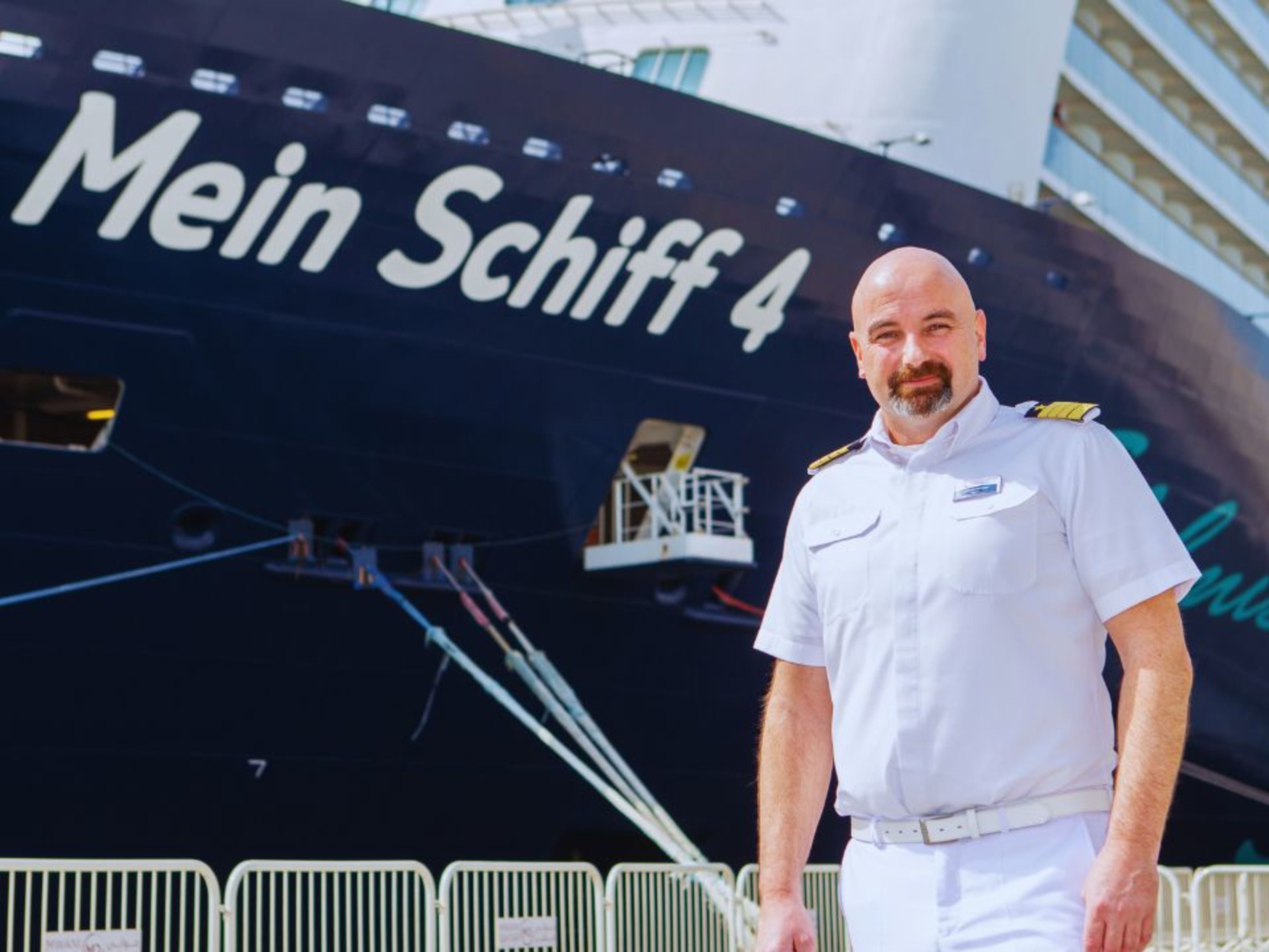 Kapitän in weißer Uniform vor Kreuzfahrtschiff der Mein Schiff® Flotte. Kapitän in weißer Uniform vor Kreuzfahrtschiff der Mein Schiff® Flotte.