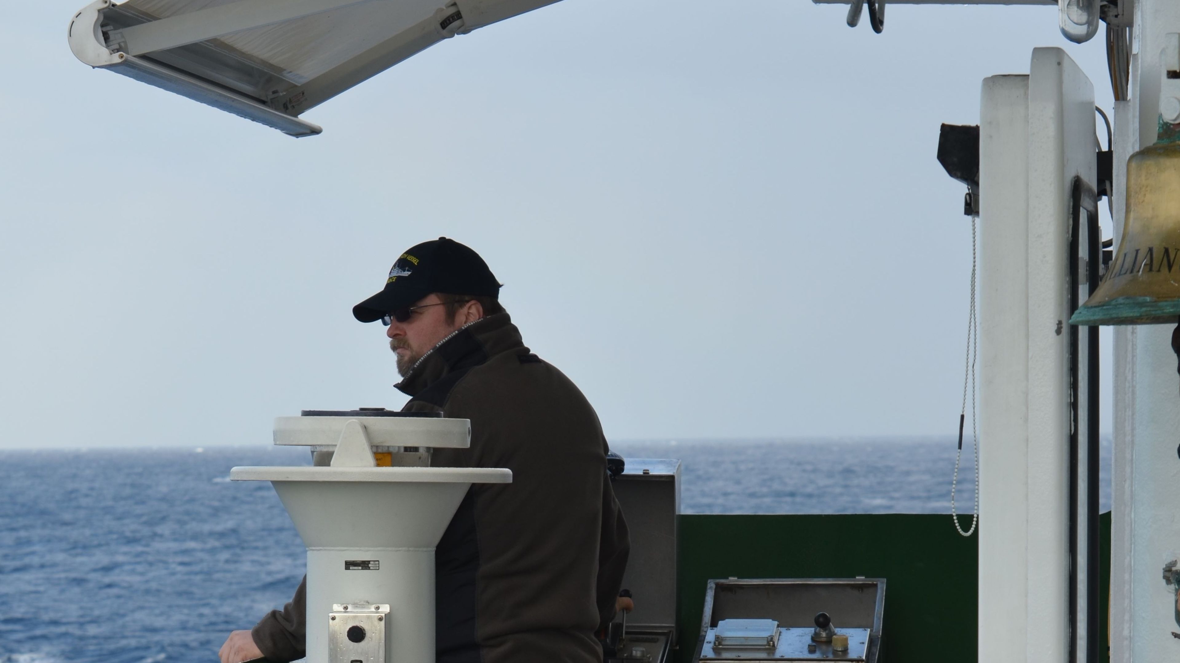 Kapitän Jan Schubert Mann mit Mütze auf Schiff, Meer im Hintergrund.