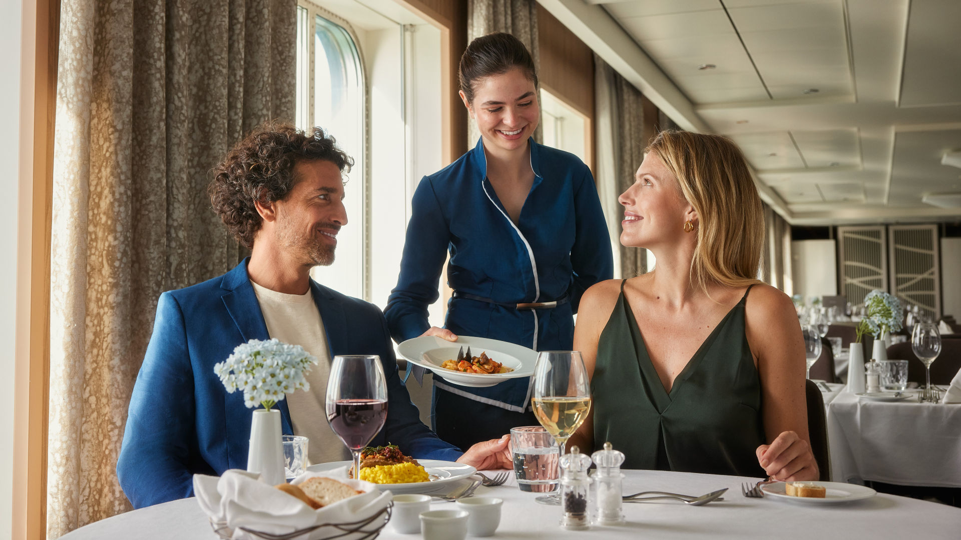 Paar genießt Abendessen, Kellnerin serviert, elegante Atmosphäre, Kreuzfahrtschiff.