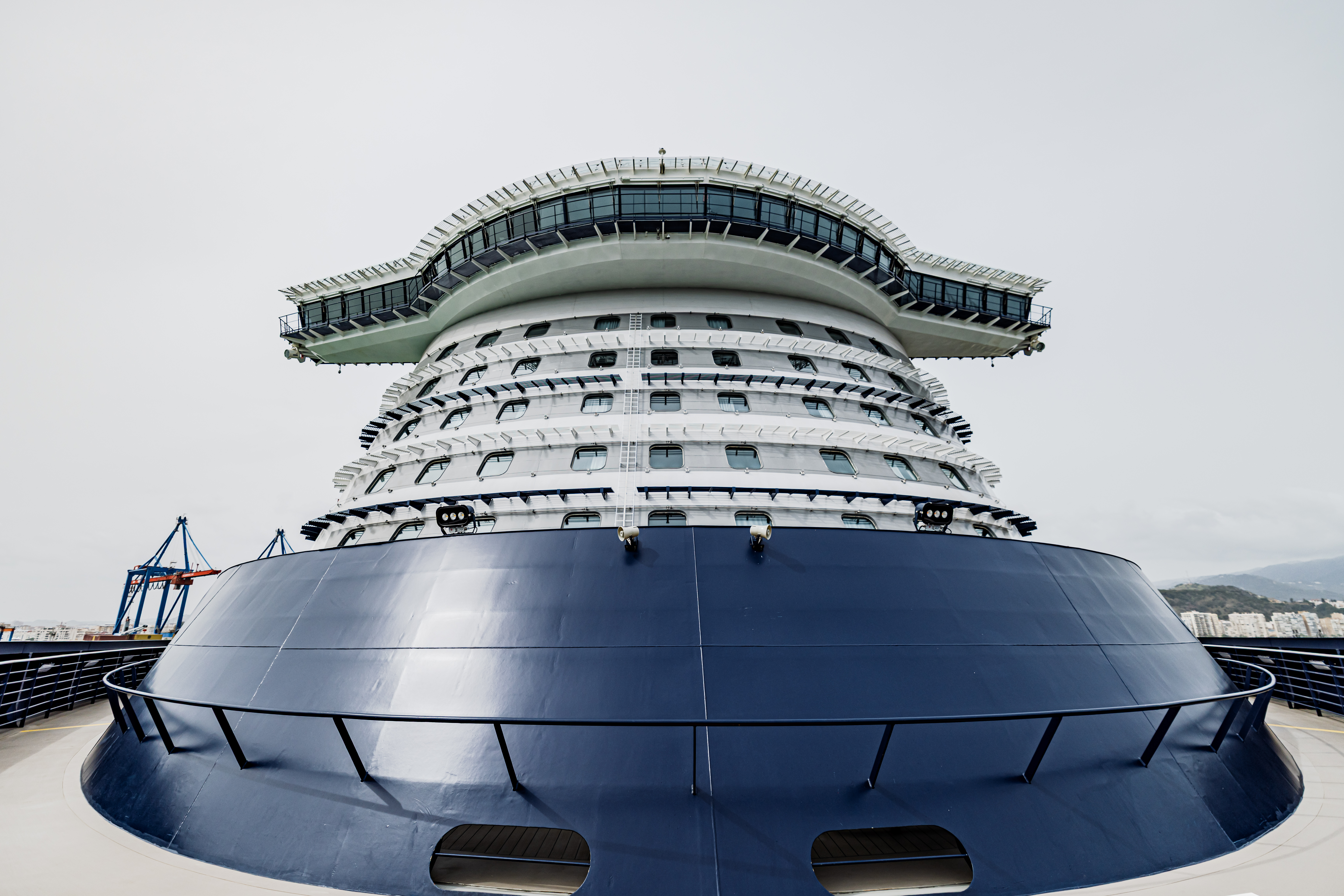 Kreuzfahrtschiff der Mein Schiff® Flotte, blauer Rumpf, Hafenhintergrund.