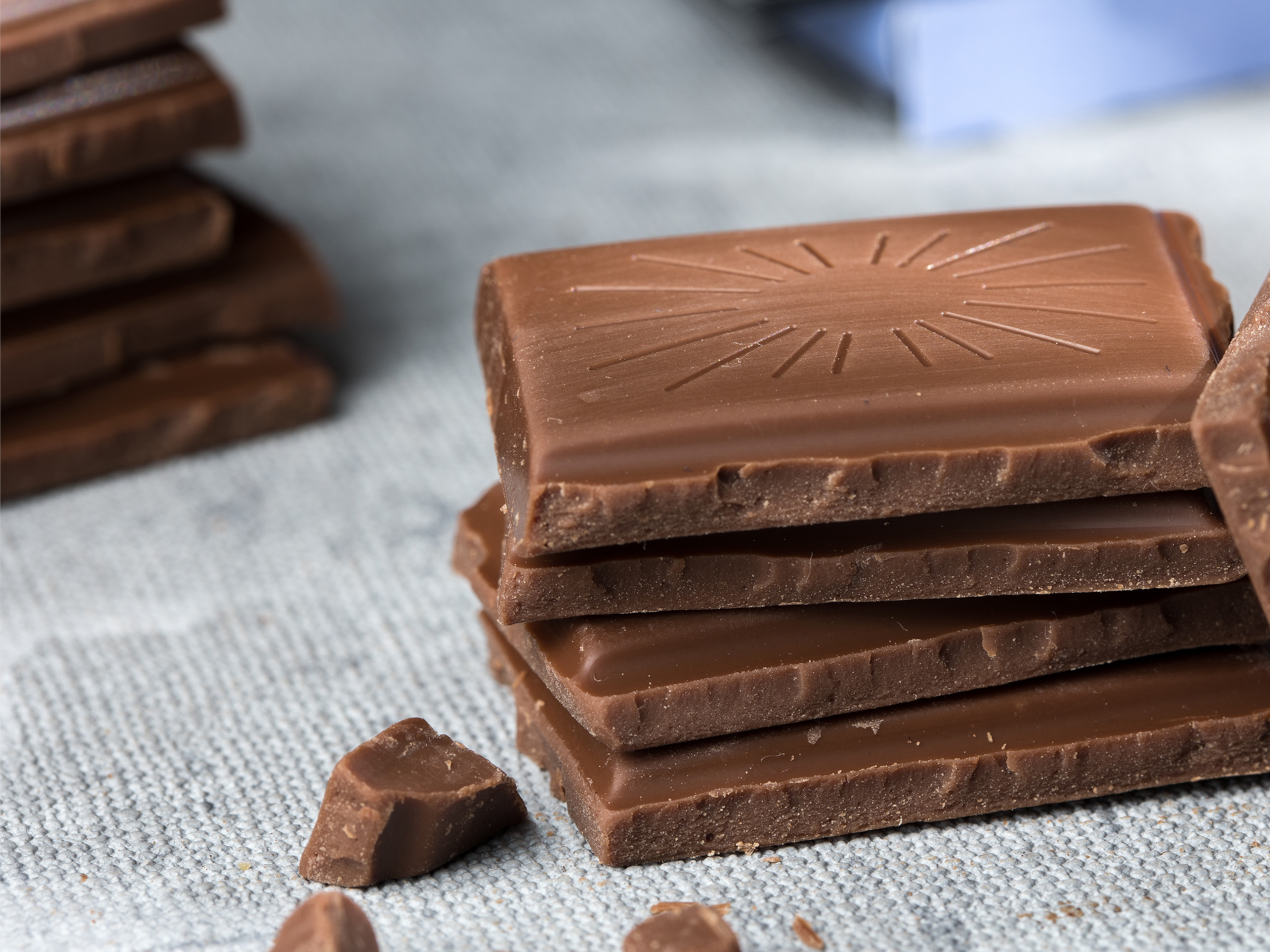 Original Beans Vollmilch Stapel von Milchschokoladenstücken auf grauem Stoff.