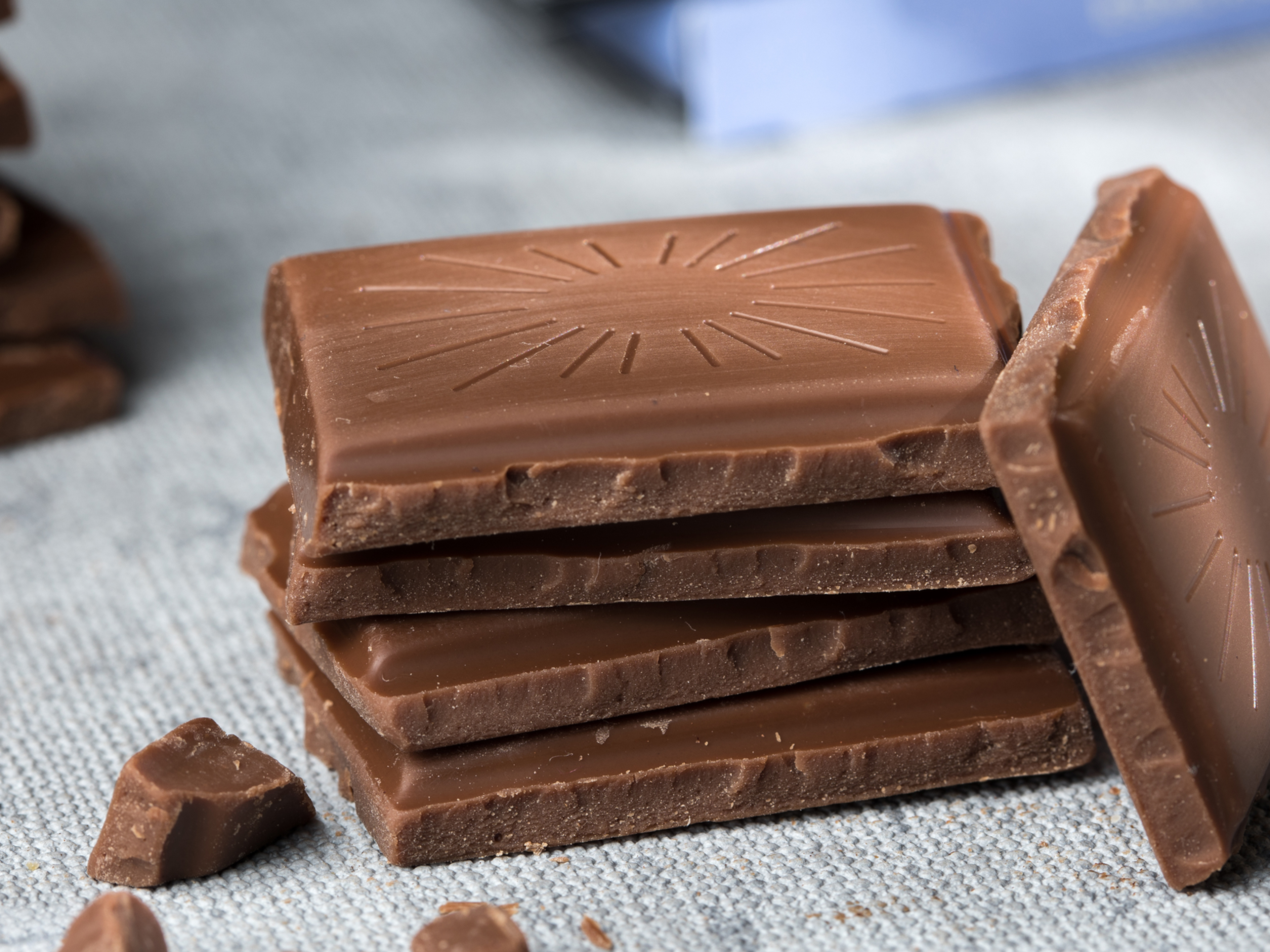 Stapel von Milchschokoladenstücken auf grauem Stoff. Stapel von Milchschokoladenstücken auf grauem Stoff.