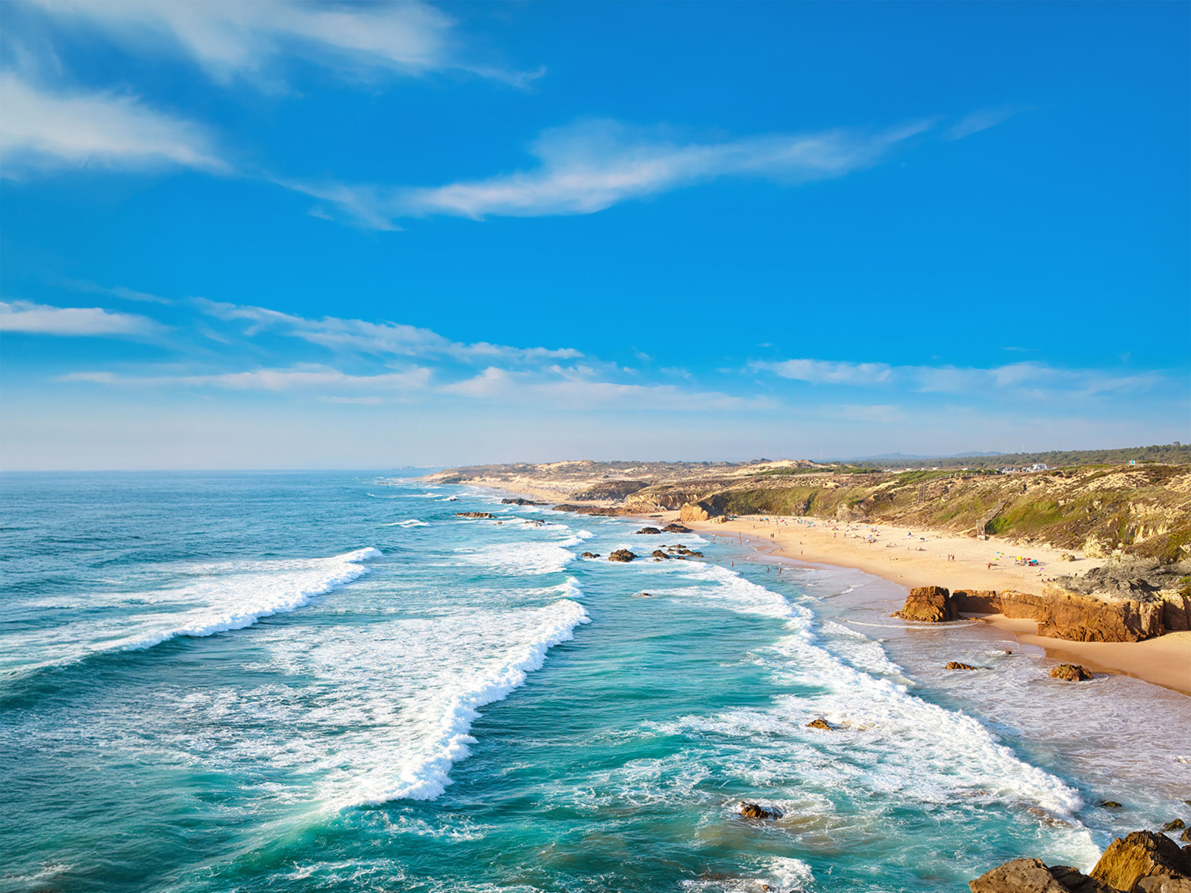 Atlantikküste Portugal Küste mit Wellen, blauem Himmel und Sandstrand in Portugal.