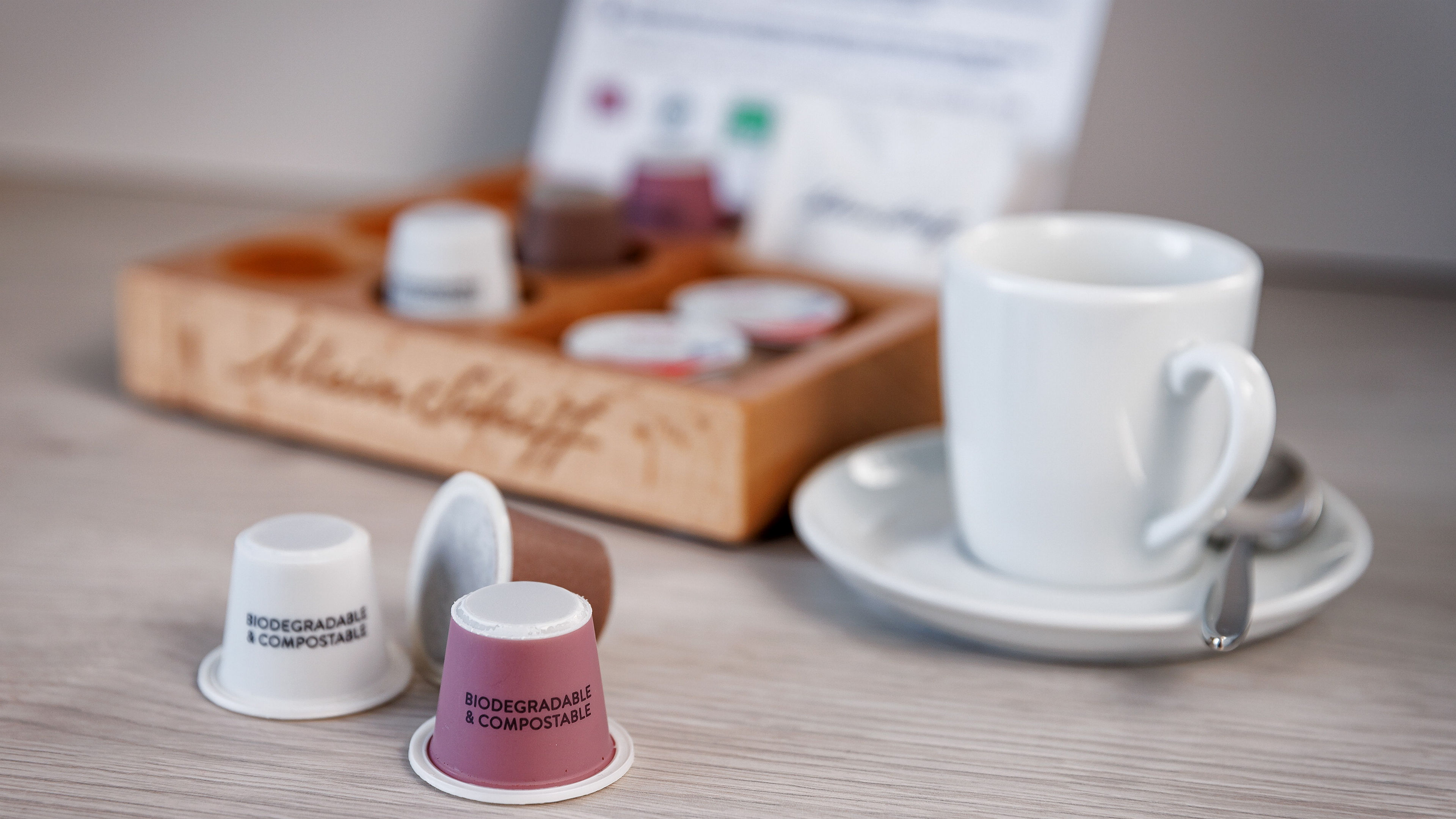 Biologisch abbaubare Kaffeekapseln und weiße Tasse auf Tisch.