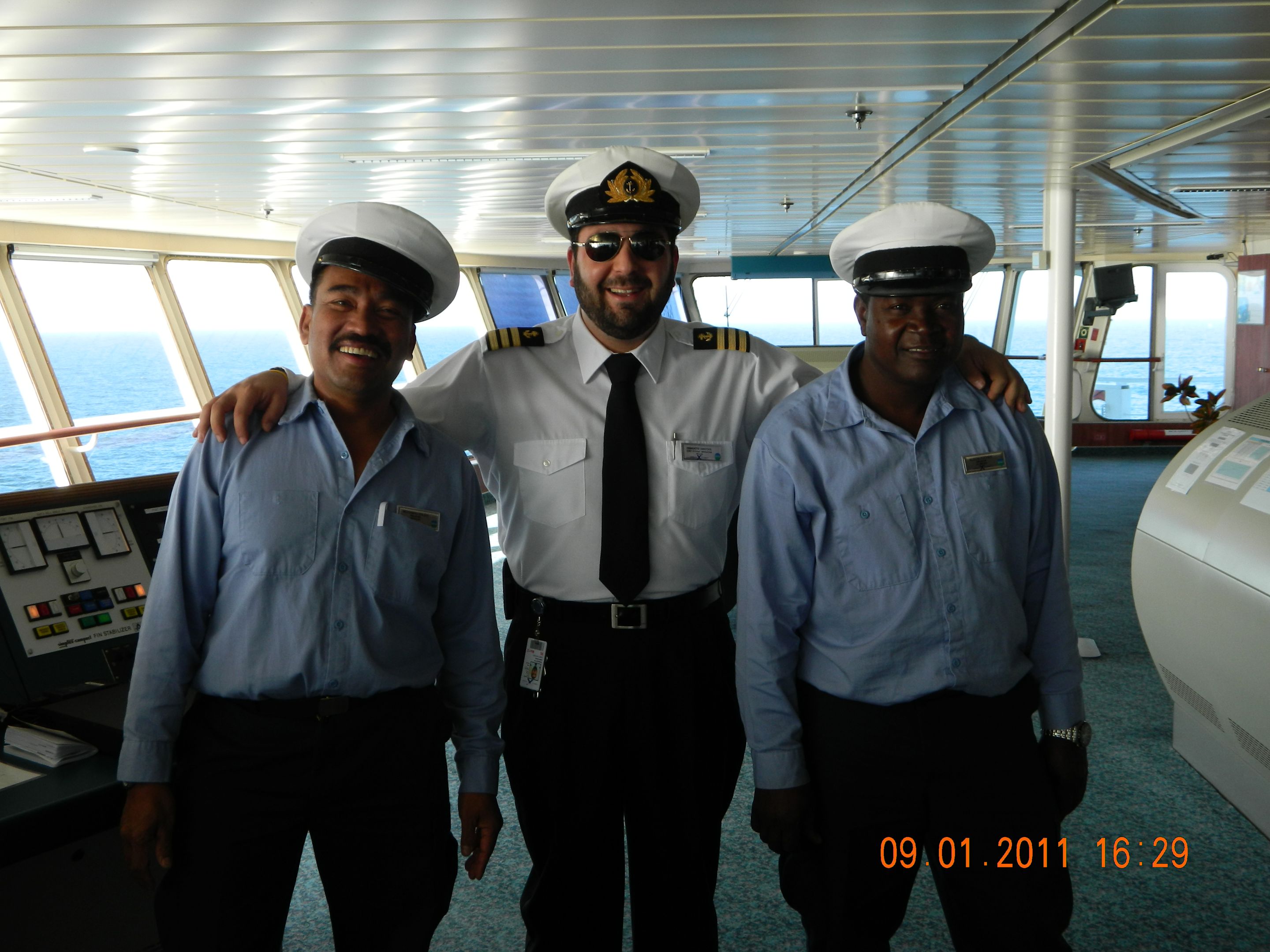 Drei Männer in Uniform auf der Brücke eines Kreuzfahrtschiffs.