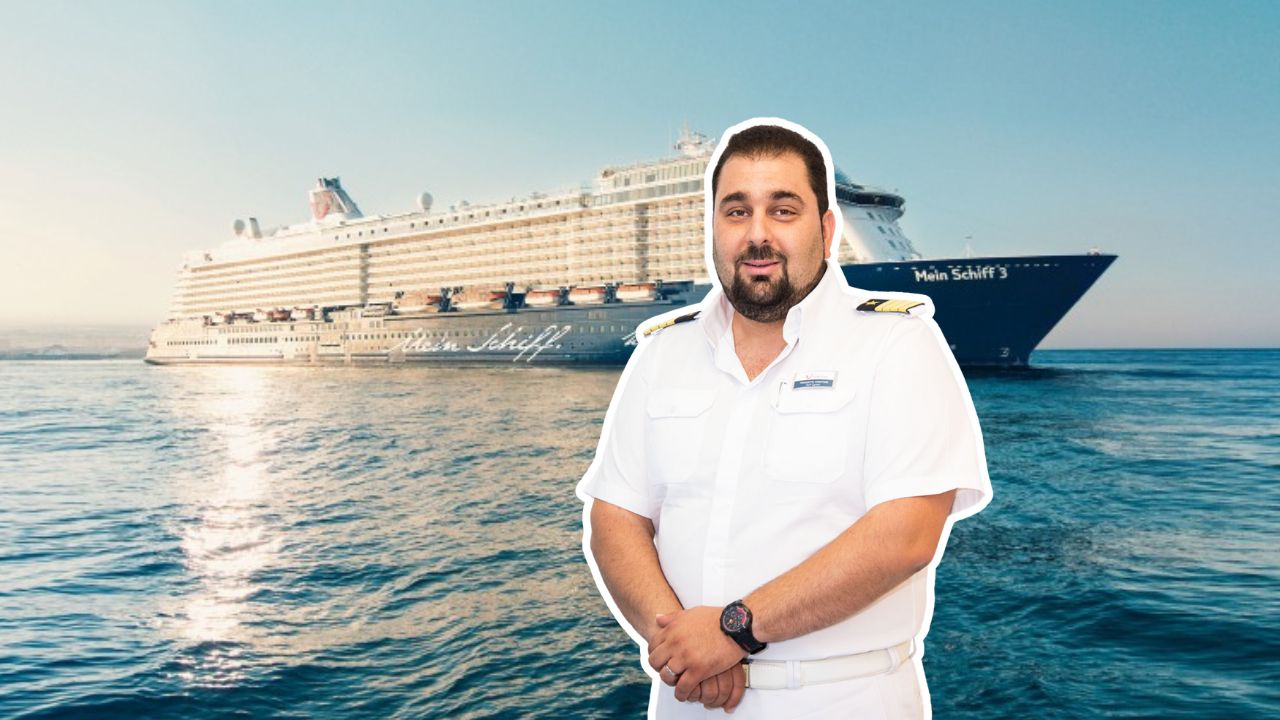 Mann in Uniform vor Kreuzfahrtschiff der Mein Schiff® Flotte auf offenem Meer.