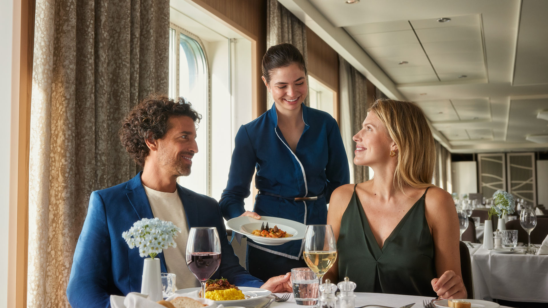 Paar genießt Abendessen auf Kreuzfahrtschiff, Kellnerin serviert Essen.