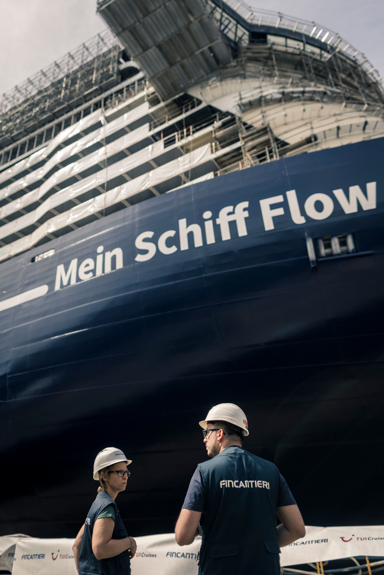 Zwei Arbeiter vor Kreuzfahrtschiff der Mein Schiff® Flotte im Bau.