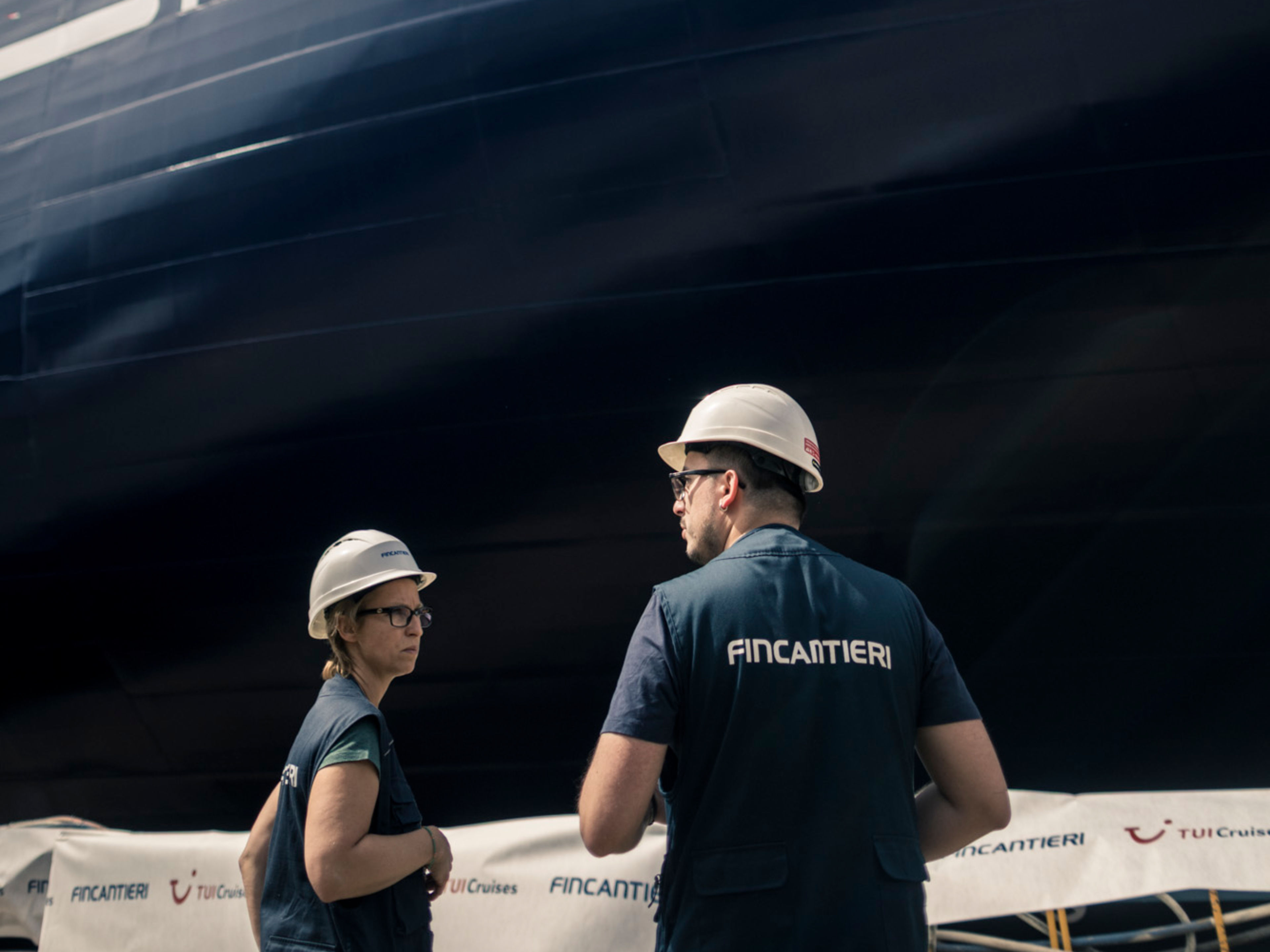 Aufschwimmen Mein Schiff Flow Zwei Arbeiter vor Kreuzfahrtschiff der Mein Schiff® Flotte im Bau.