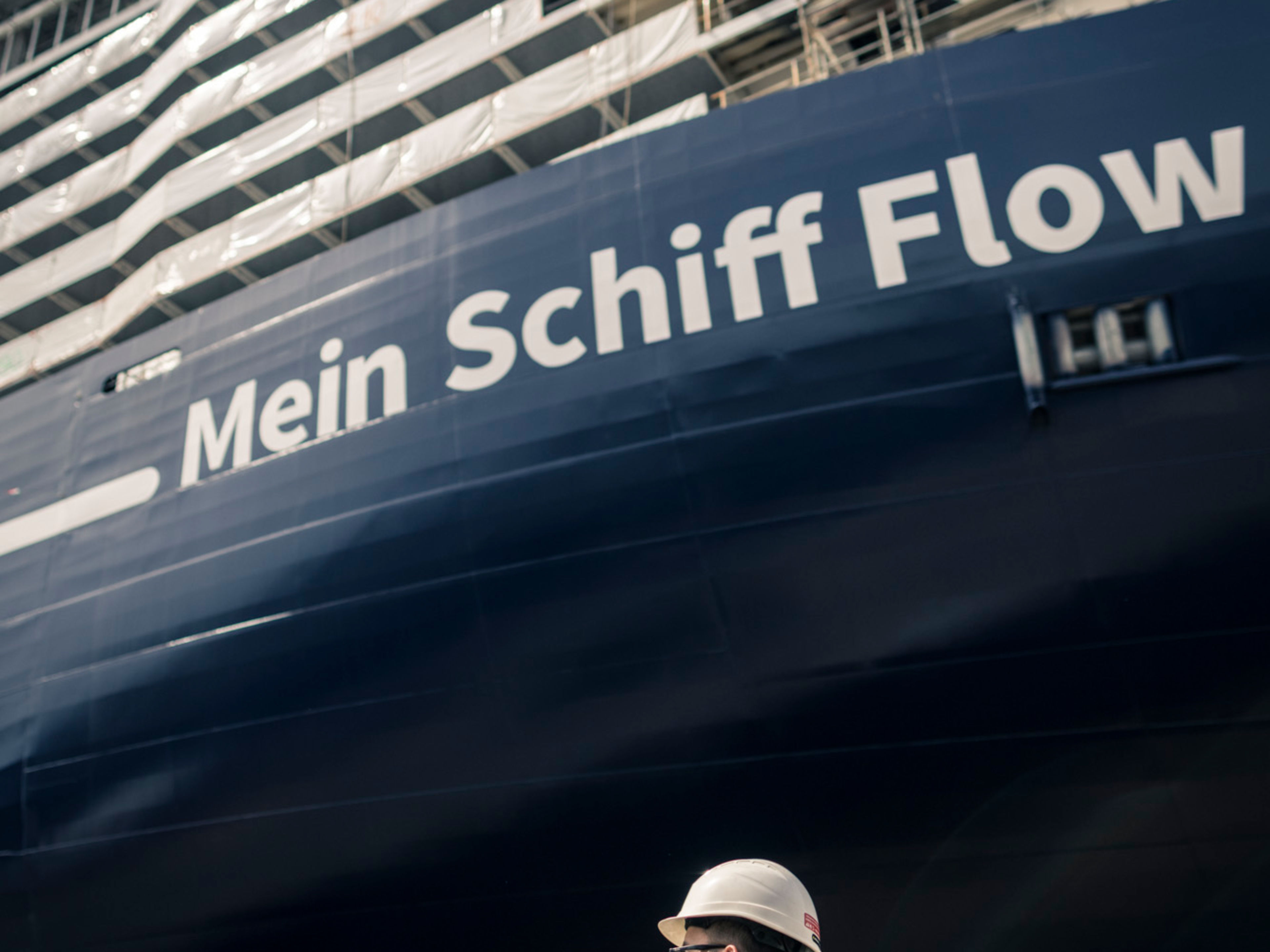 Zwei Arbeiter vor Kreuzfahrtschiff der Mein Schiff® Flotte im Bau. Zwei Arbeiter vor Kreuzfahrtschiff der Mein Schiff® Flotte im Bau.