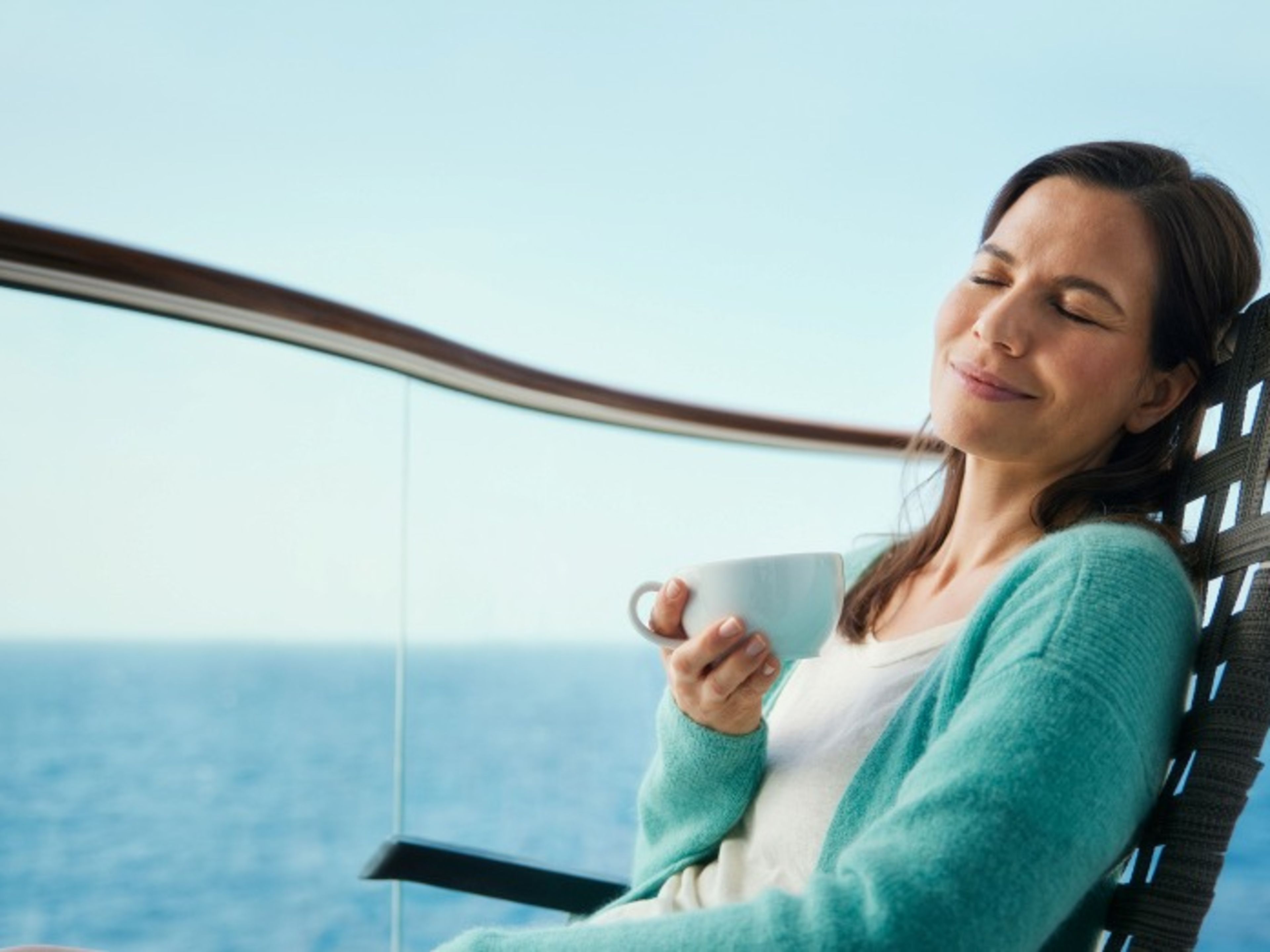 Frau entspannt mit Tasse auf Kreuzfahrtschiff, Meerblick. Frau entspannt mit Tasse auf Kreuzfahrtschiff, Meerblick.