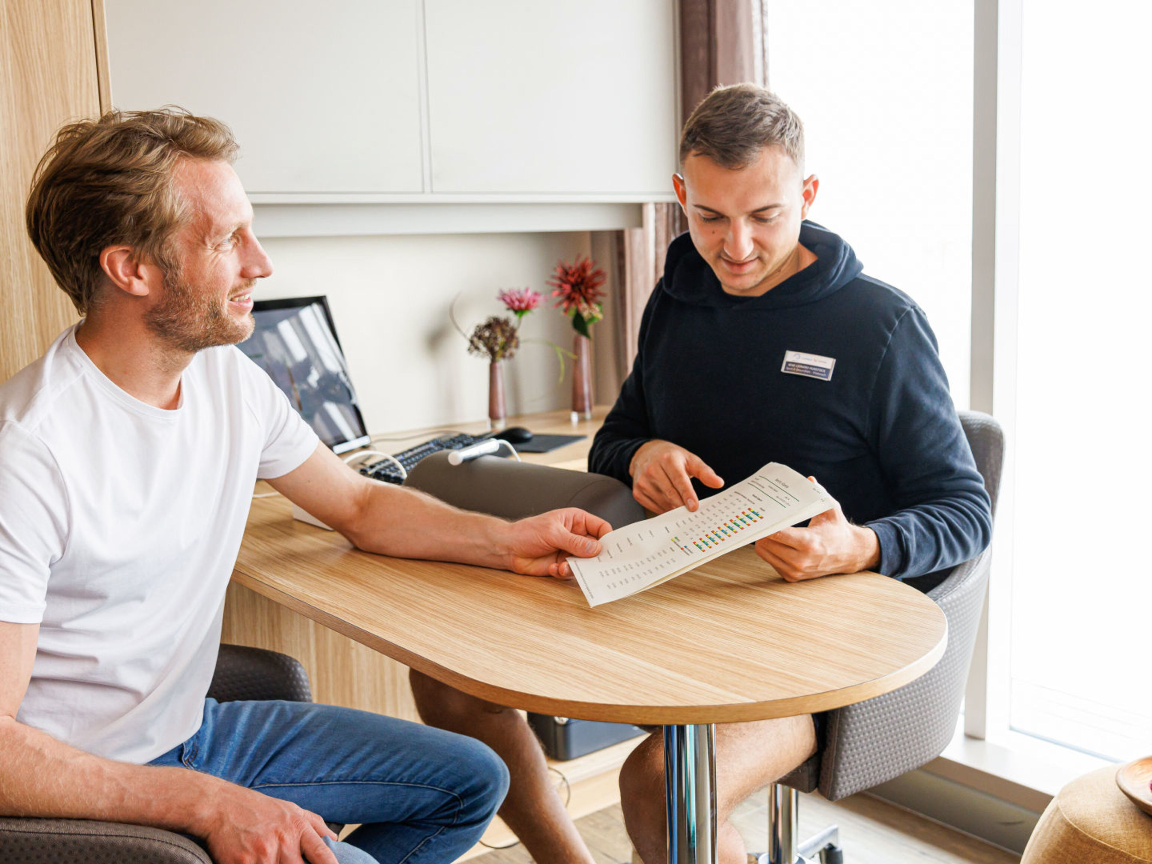 Zwei Männer am Tisch, besprechen Dokument, helle Umgebung. Zwei Männer am Tisch, besprechen Dokument, helle Umgebung.