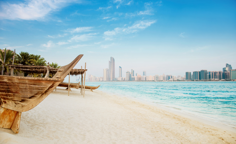 Strand mit traditionellen Booten und Skyline von Abu Dhabi.
