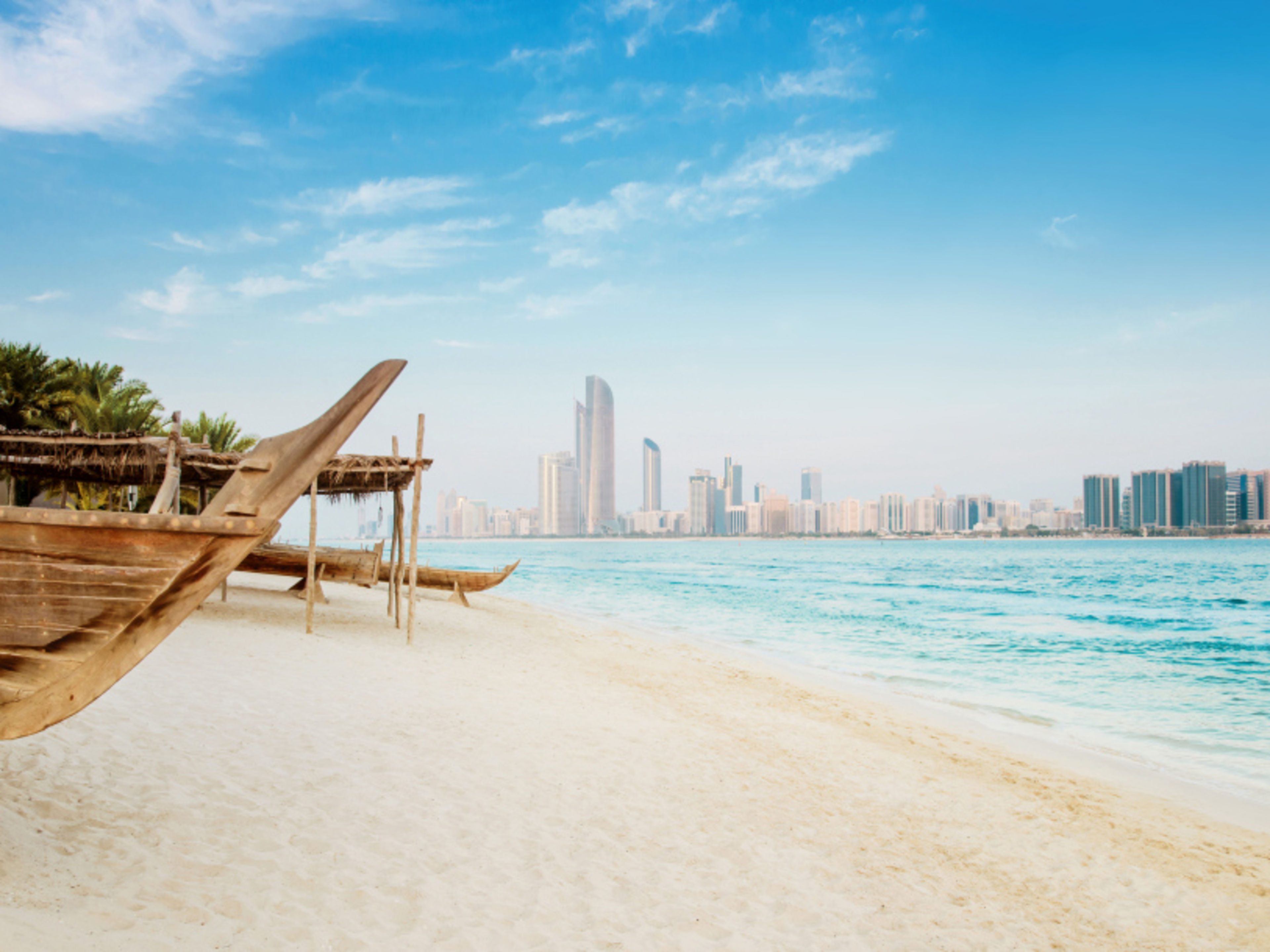 Abu Dhabi Strand mit traditionellen Booten und Skyline von Abu Dhabi.