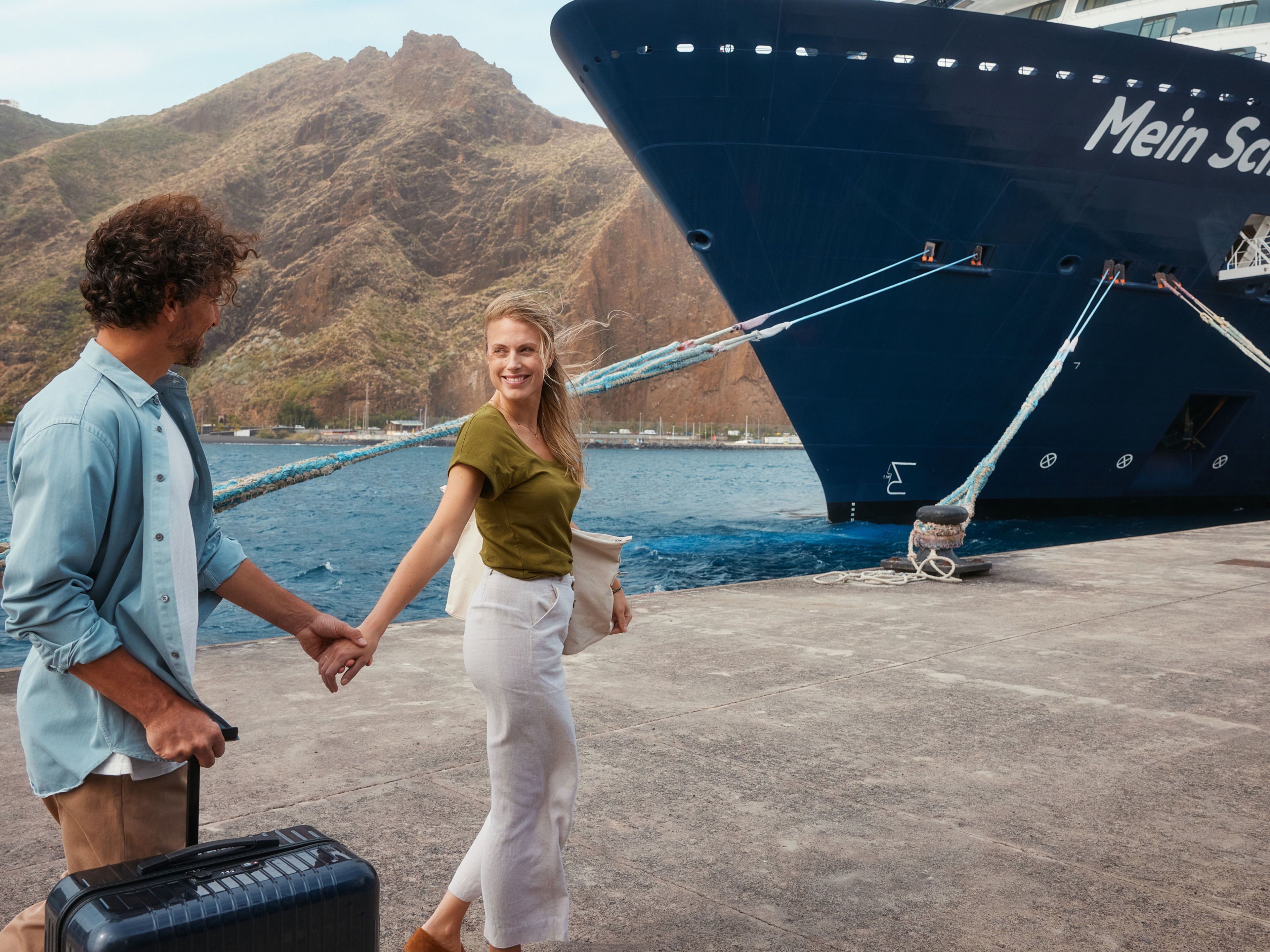 Paar am Hafen vor Kreuzfahrtschiff der Mein Schiff® Flotte, Berge im Hintergrund. Paar am Hafen vor Kreuzfahrtschiff der Mein Schiff® Flotte, Berge im Hintergrund.