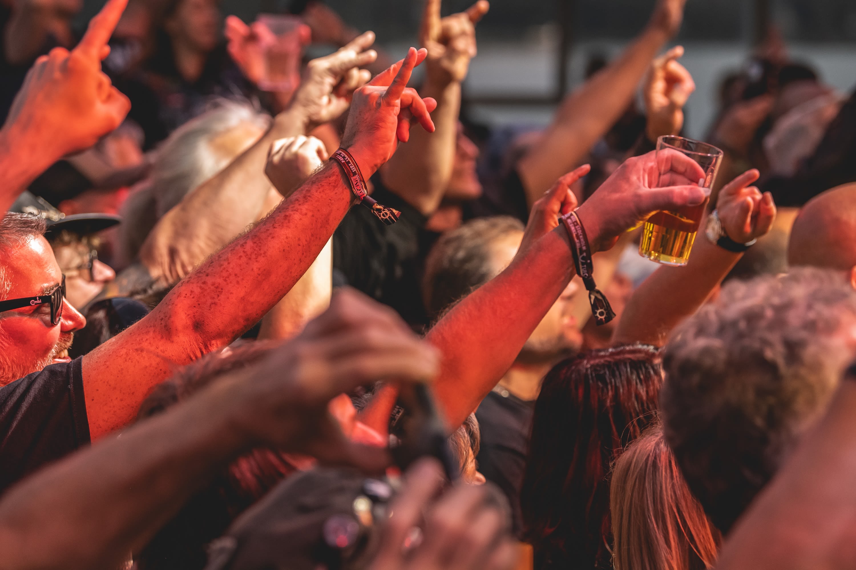 Menschenmenge bei Konzert, Hände in der Luft, Bierglas, Festivalstimmung.