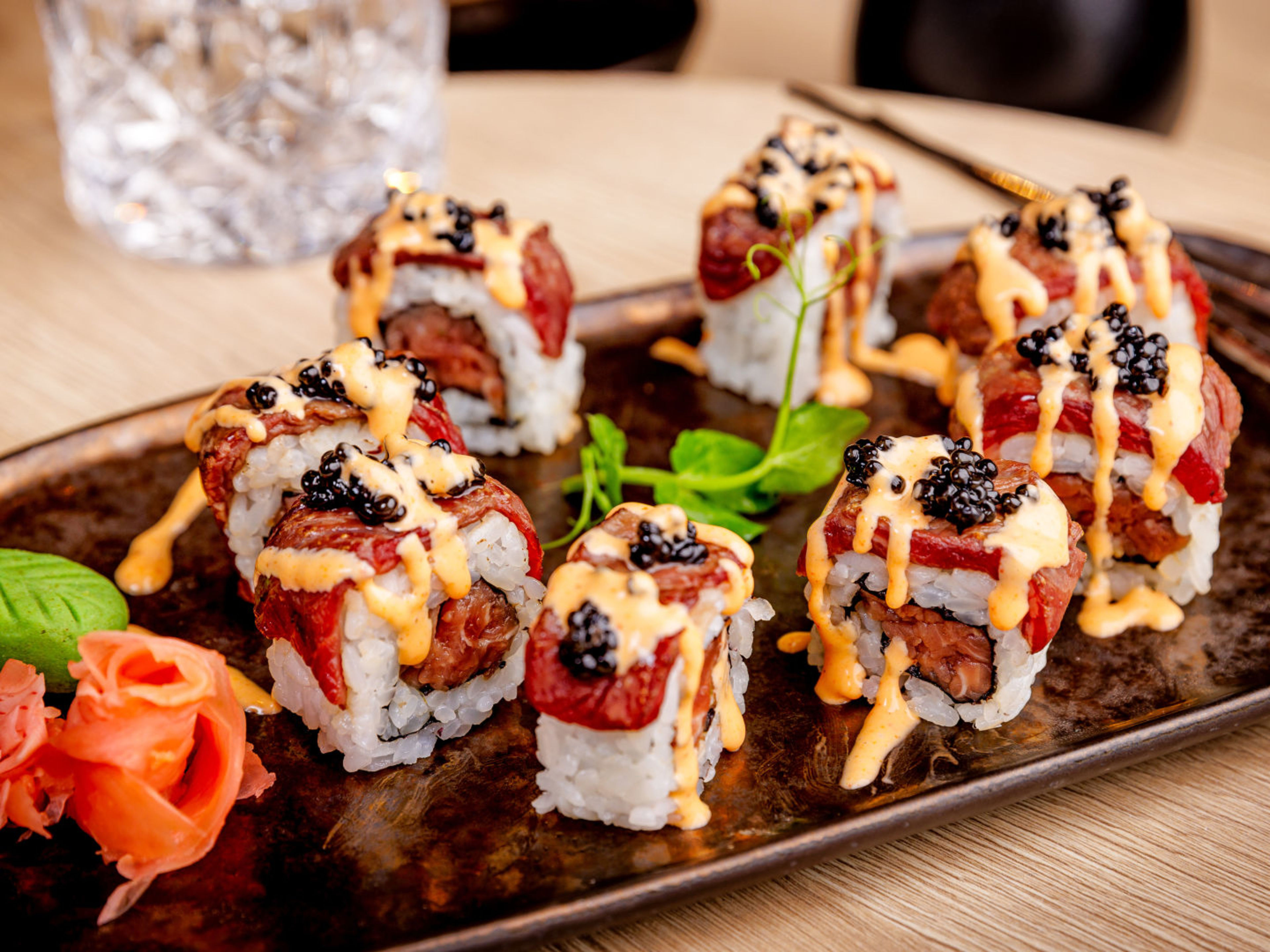 Sushi-Rollen mit Lachs, Kaviar und Sauce auf schwarzem Teller. Sushi-Rollen mit Lachs, Kaviar und Sauce auf schwarzem Teller.