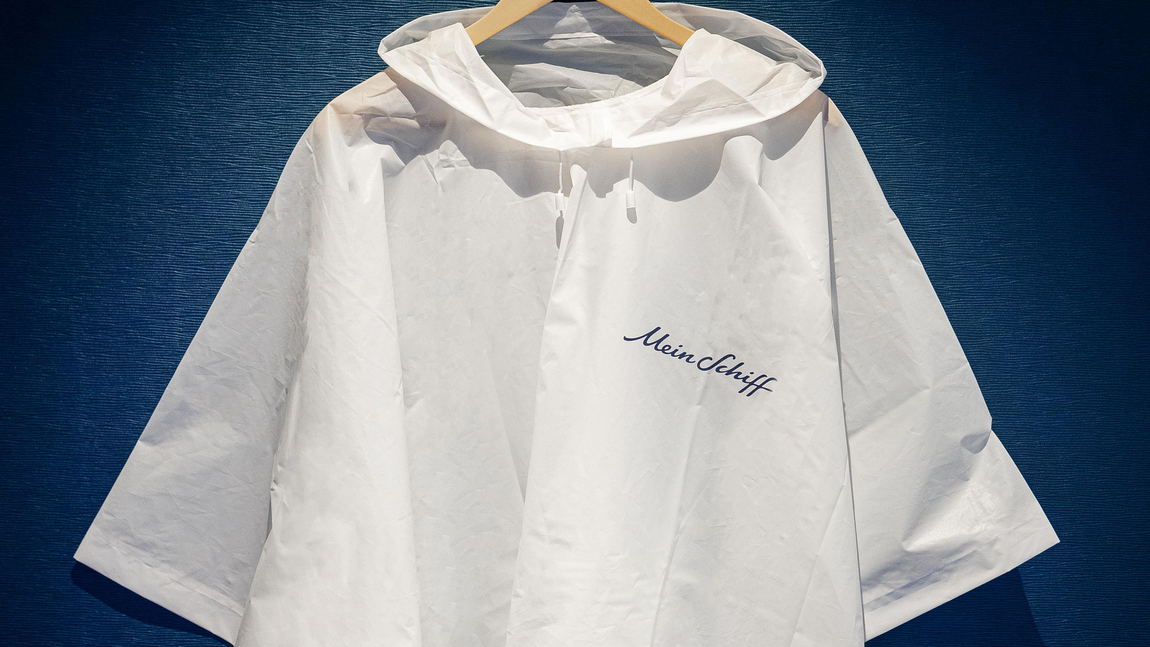 Weiße Regenjacke mit "Mein Schiff" Logo auf blauem Hintergrund.