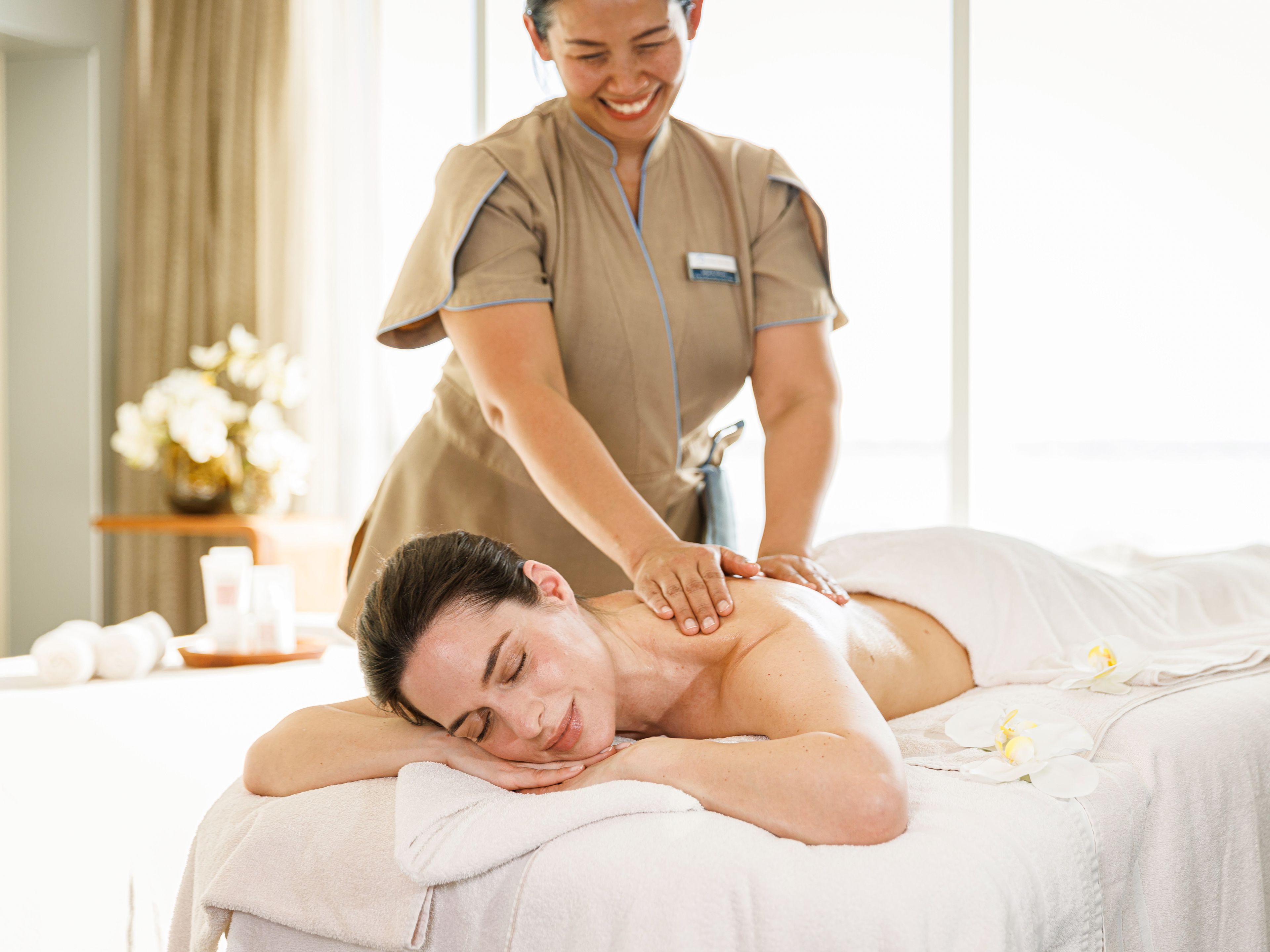 Massage - Spa & Sport Frau genießt entspannende Massage in hellem Spa-Raum.