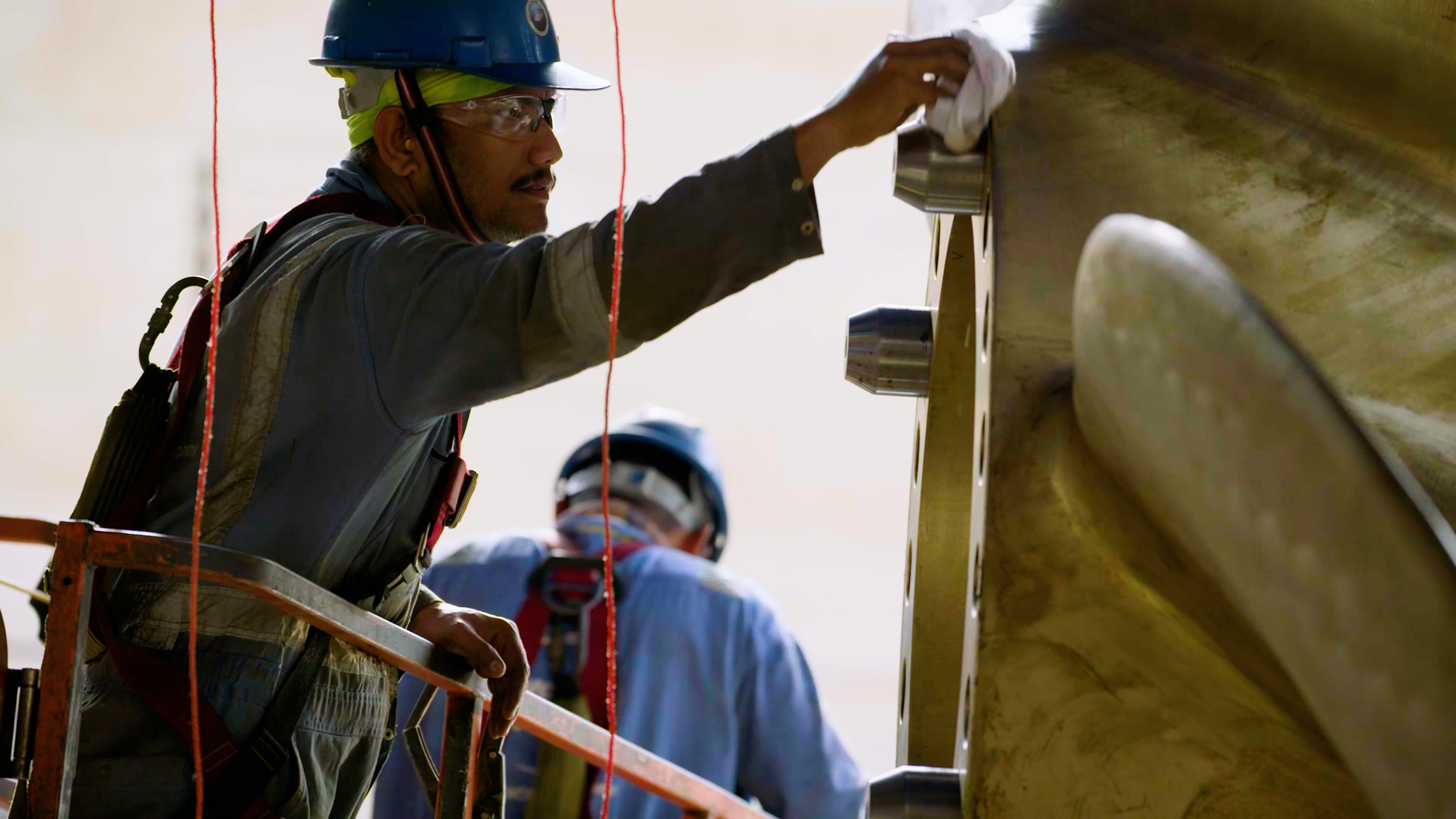 Mein Schiff 4 im Drydock Dubai Arbeiter mit Helm reinigt große Metalloberfläche.