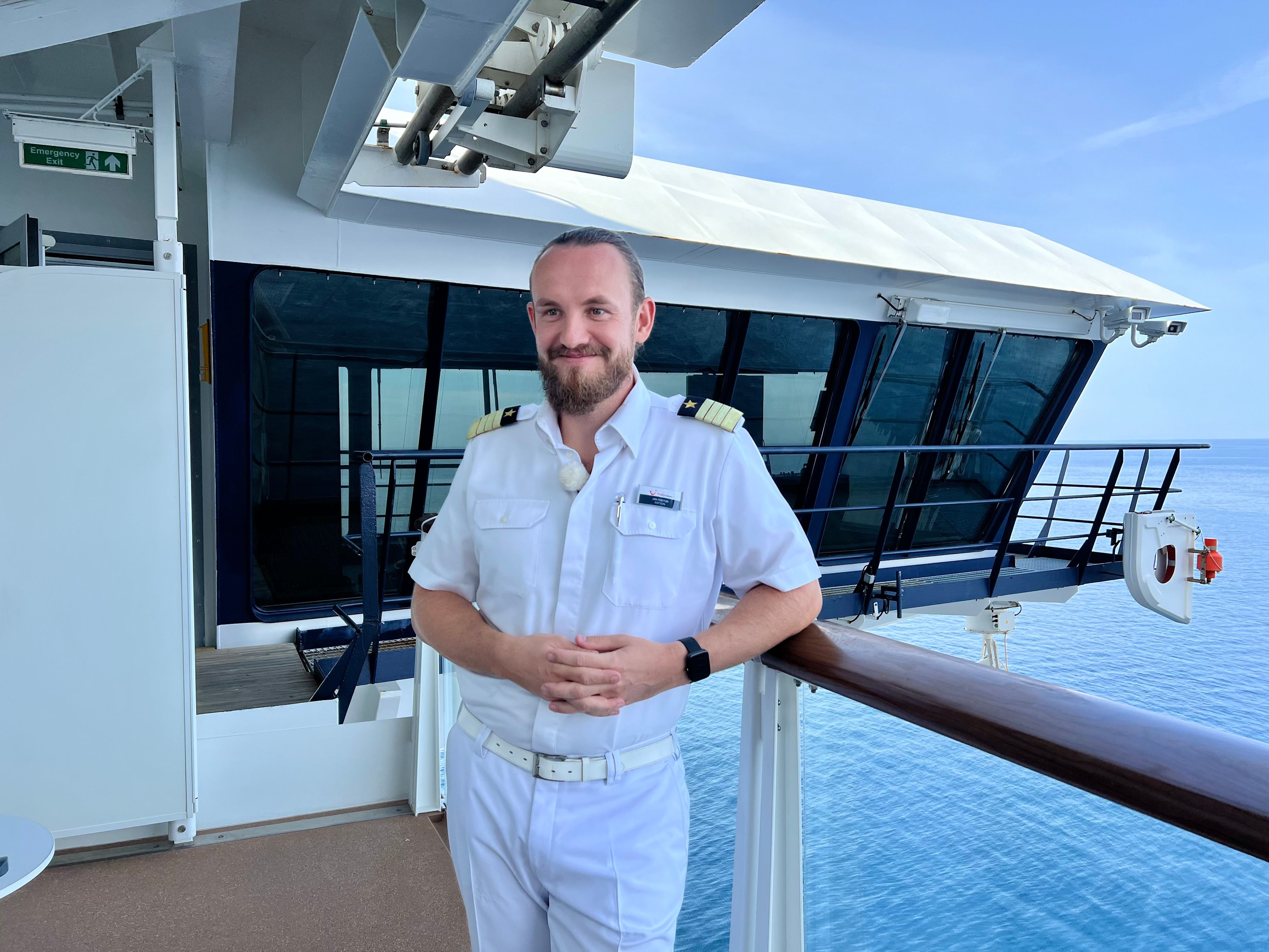 Mann in weißer Uniform auf Kreuzfahrtschiff der Mein Schiff® Flotte, Meer im Hintergrund. Mann in weißer Uniform auf Kreuzfahrtschiff der Mein Schiff® Flotte, Meer im Hintergrund.