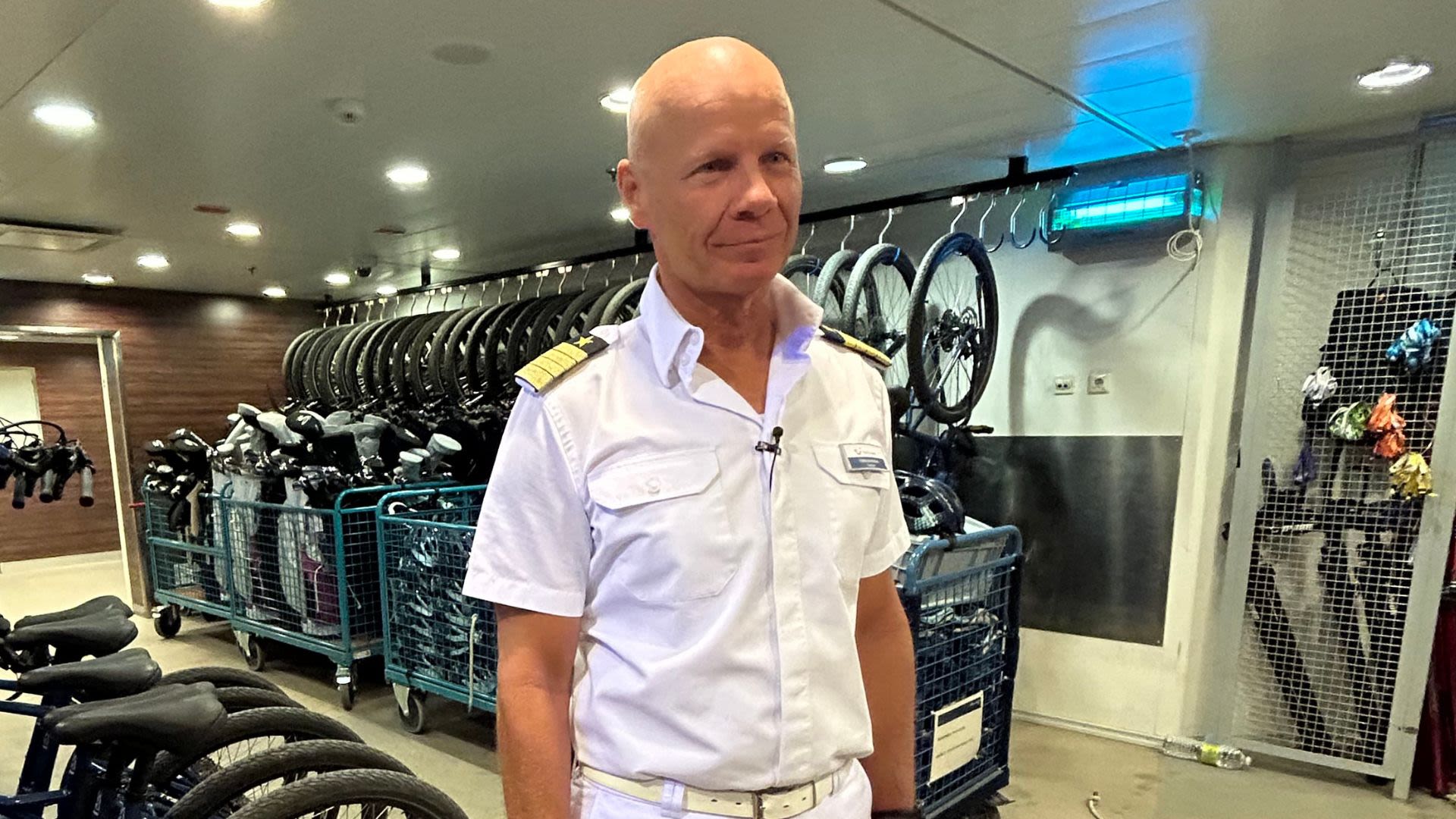 Mann in weißer Uniform vor Fahrrädern auf Kreuzfahrtschiff.
