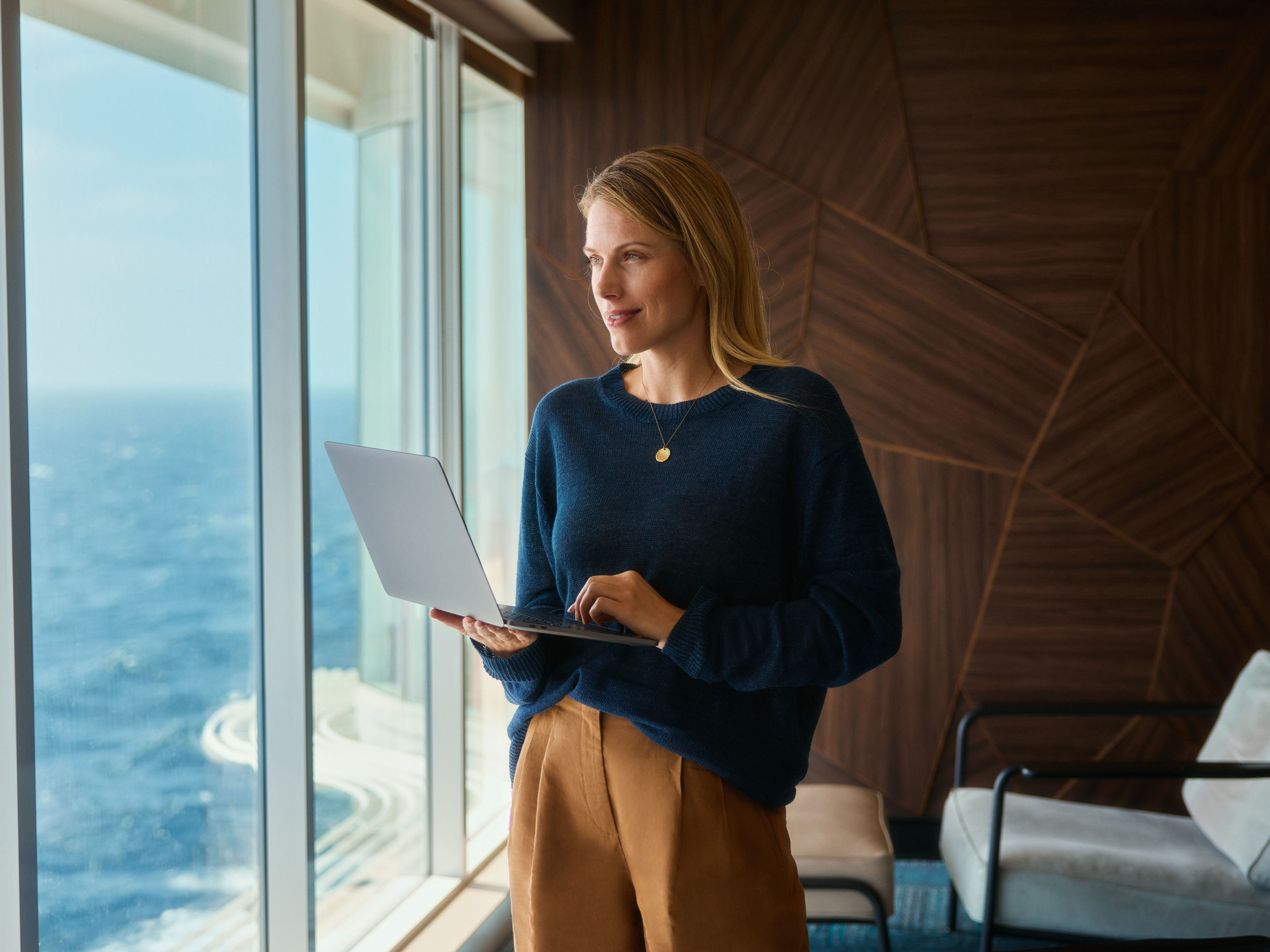 Internet an Bord nutzen Frau mit Laptop, blickt aus Fenster auf Meer.