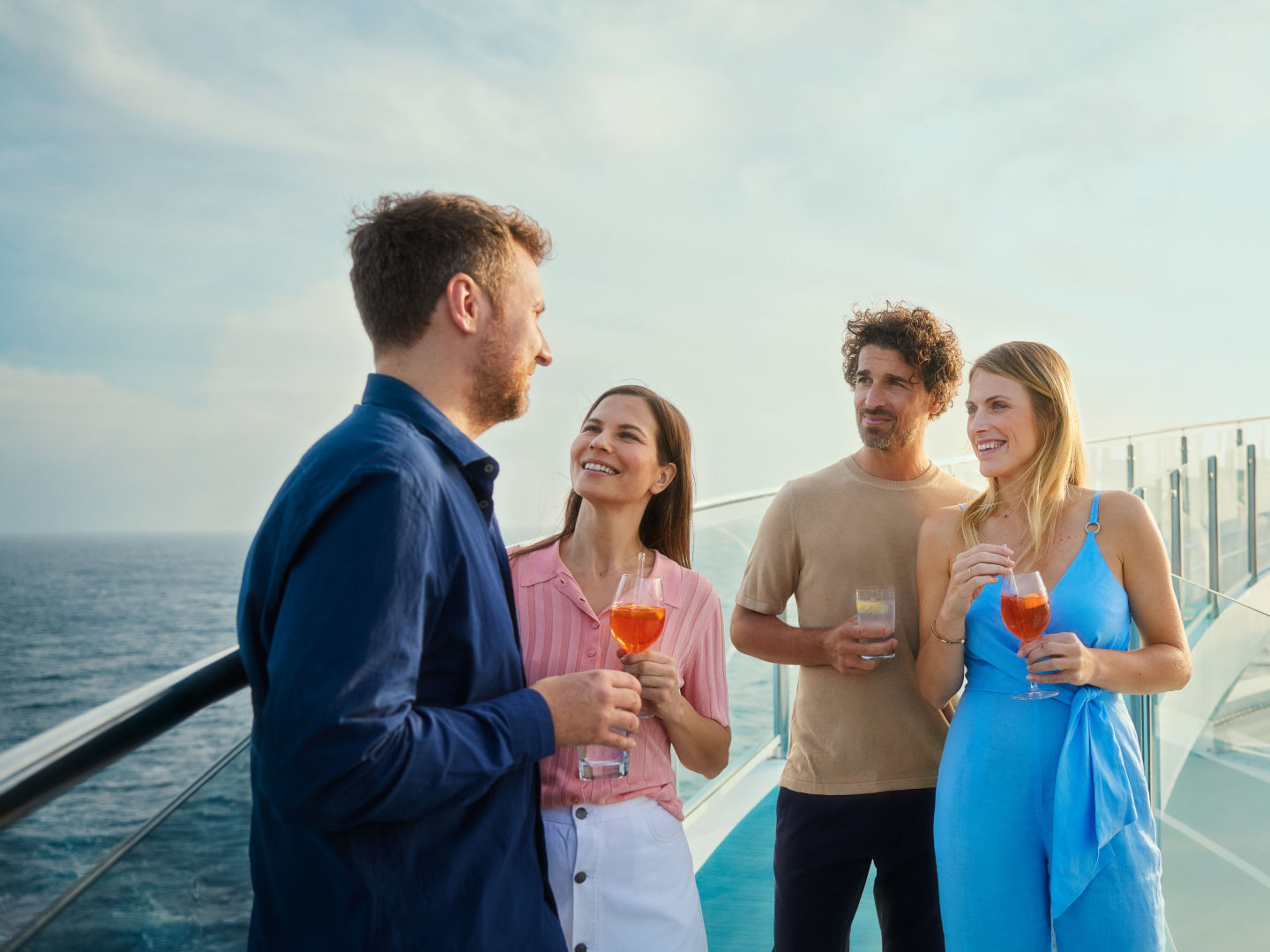 Jeder Moment erfrischend Vier Personen genießen Getränke auf einem Kreuzfahrtschiff der Mein Schiff® Flotte.