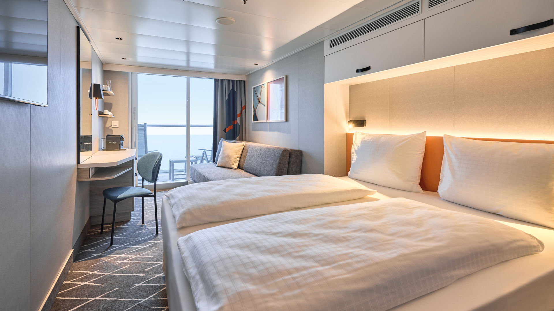 Helles Kreuzfahrtschiff-Kabine mit Doppelbett, Sofa und Balkon.