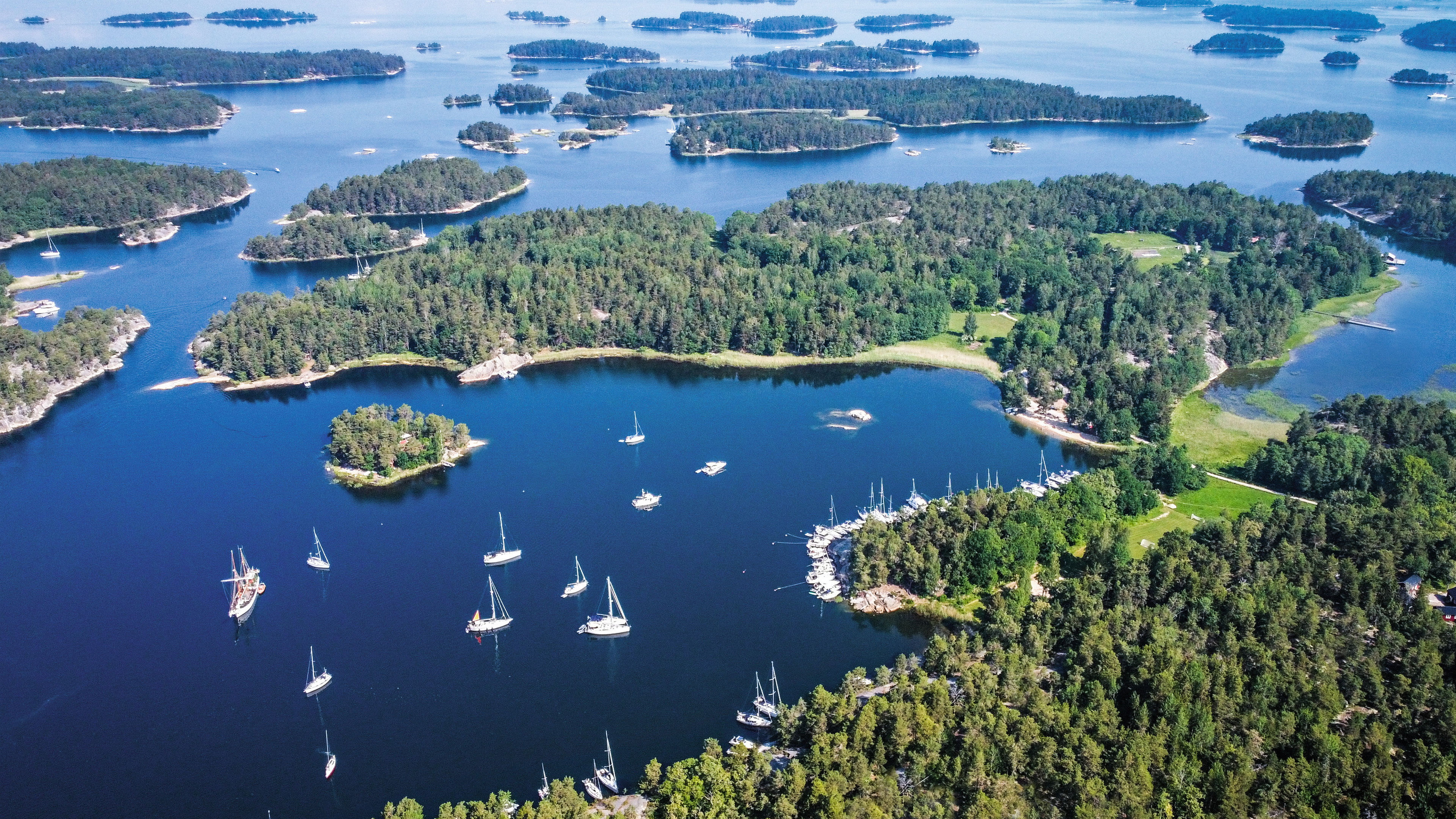 Segelboote im Schärengarten von Stockholm, umgeben von grünen Inseln.