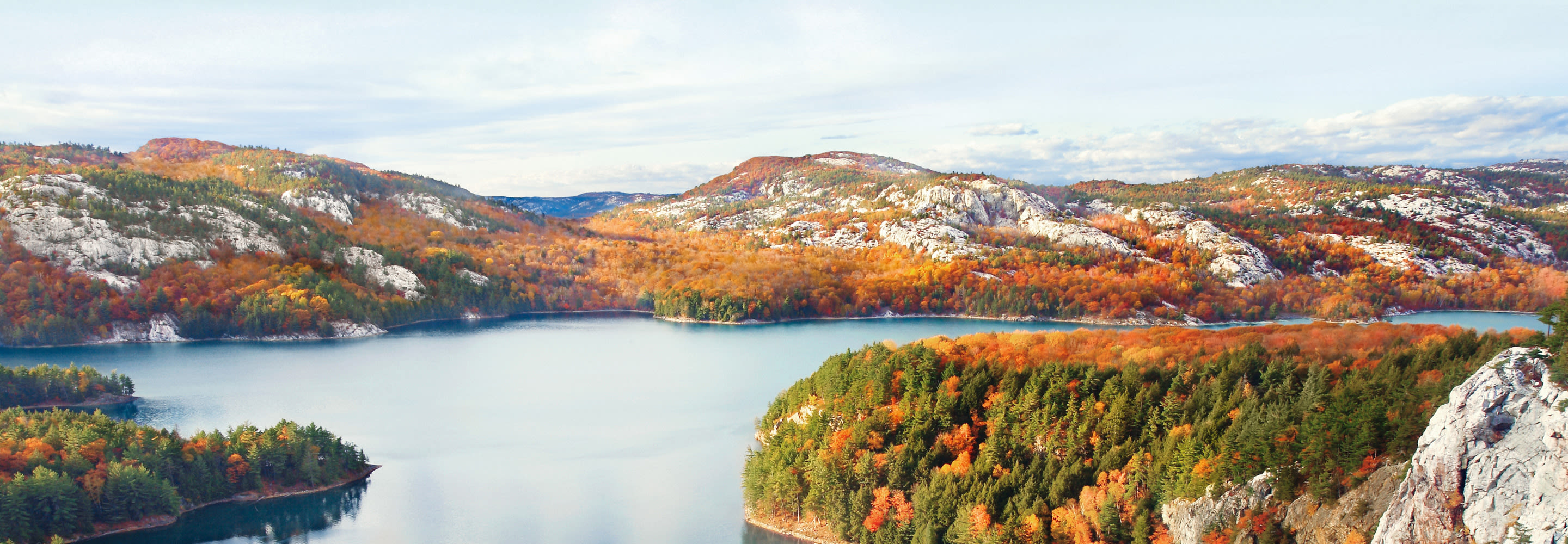 Herbstliche Landschaft mit See, bunten Bäumen und Felsen.