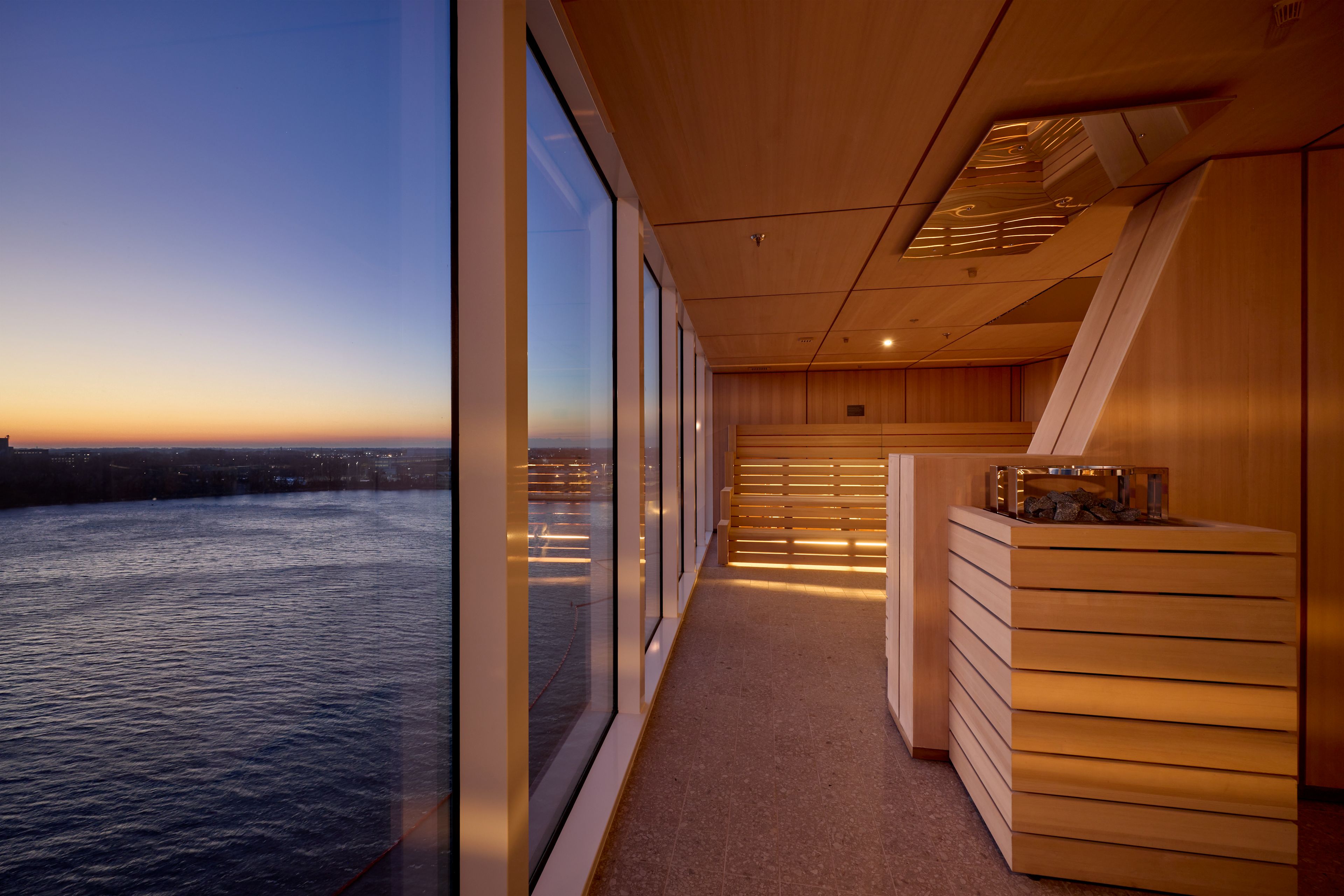 Sauna mit Panoramafenster, Blick auf Fluss bei Sonnenuntergang.