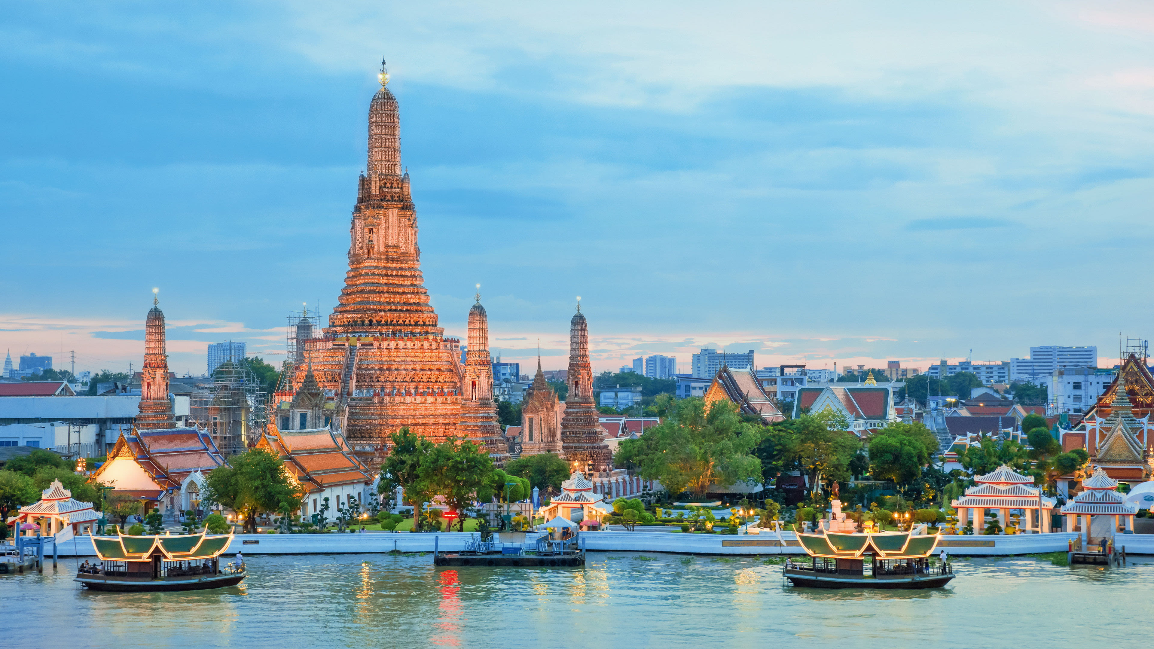Wat Arun Tempel bei Sonnenuntergang, Bangkok, mit Booten auf dem Fluss.