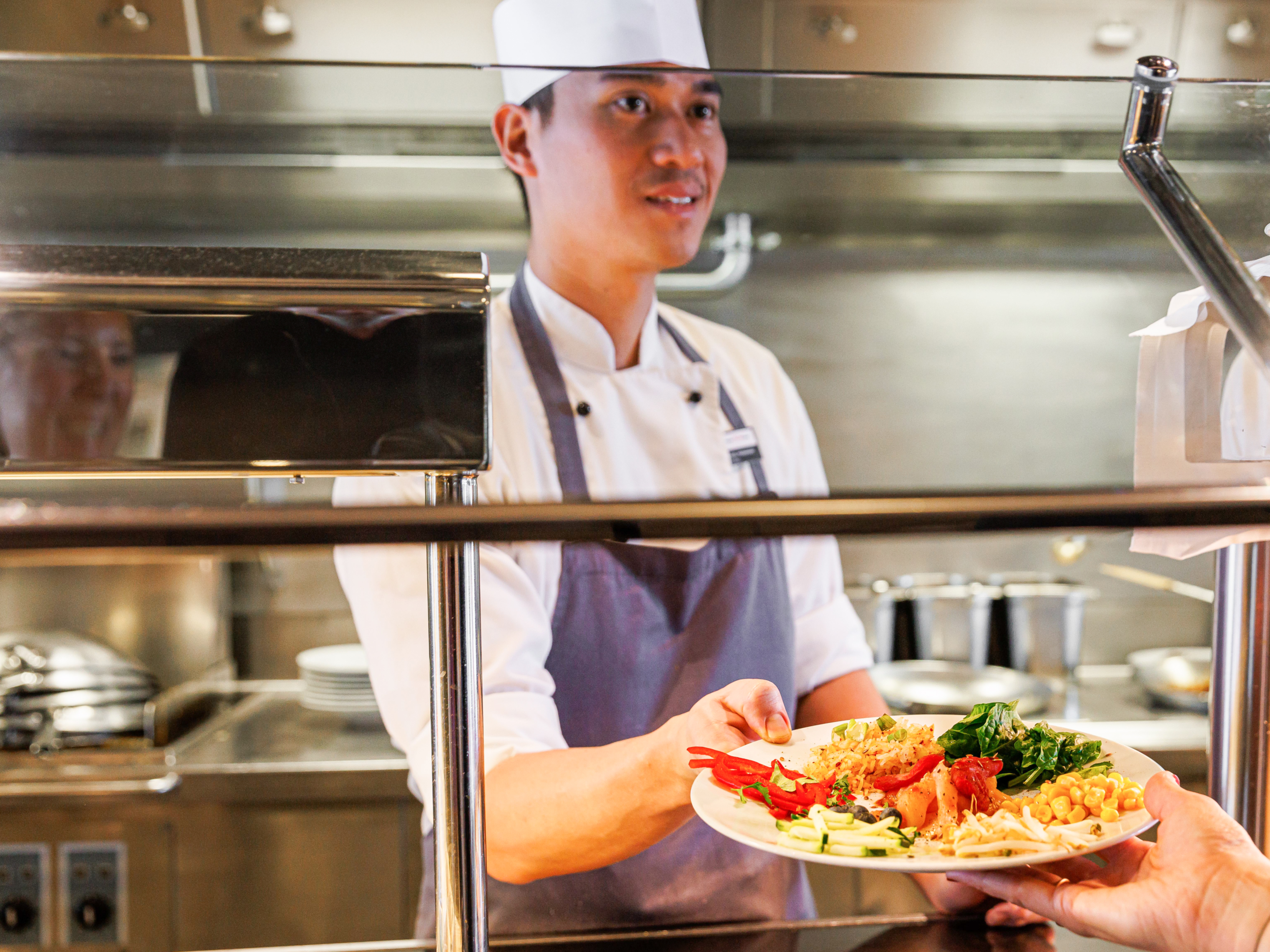 Vegetarisches Angebot an Bord Koch serviert Teller mit Gemüse und Nudeln in Kantine.