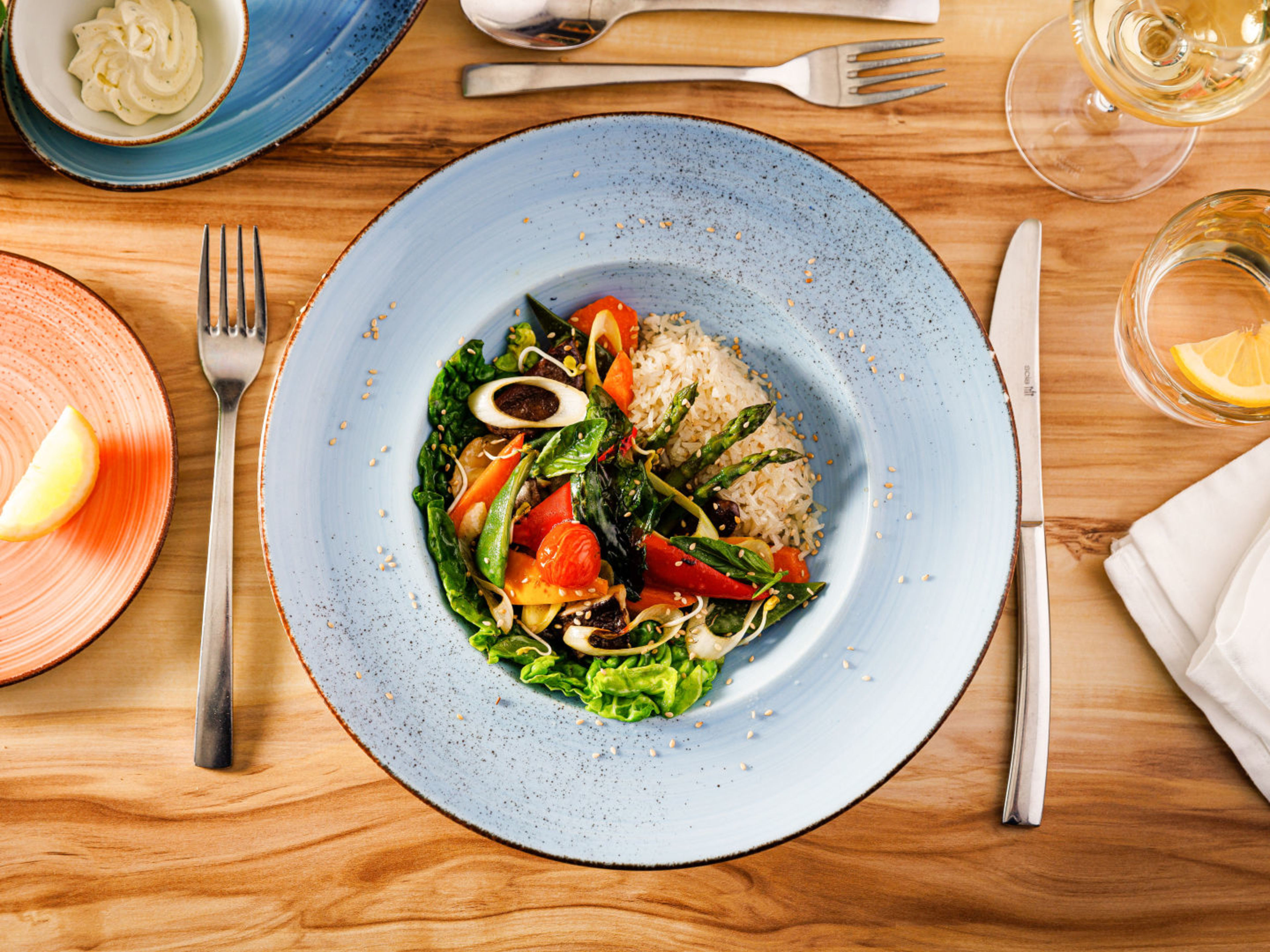 Bunter Salat mit Reis auf blauem Teller, Holztisch. Bunter Salat mit Reis auf blauem Teller, Holztisch.