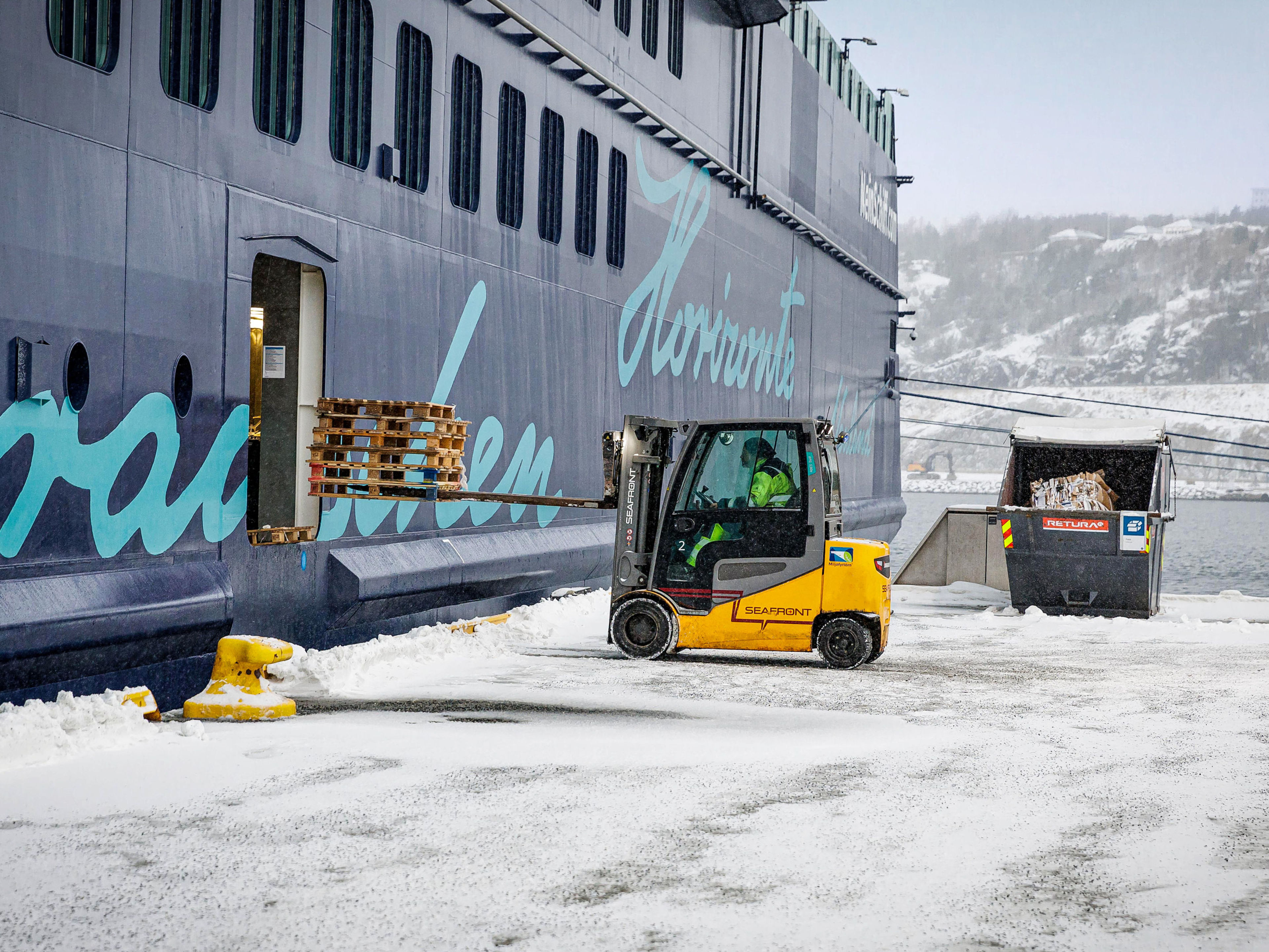 Gabelstapler lädt Paletten auf Kreuzfahrtschiff im Schnee. Gabelstapler lädt Paletten auf Kreuzfahrtschiff im Schnee.