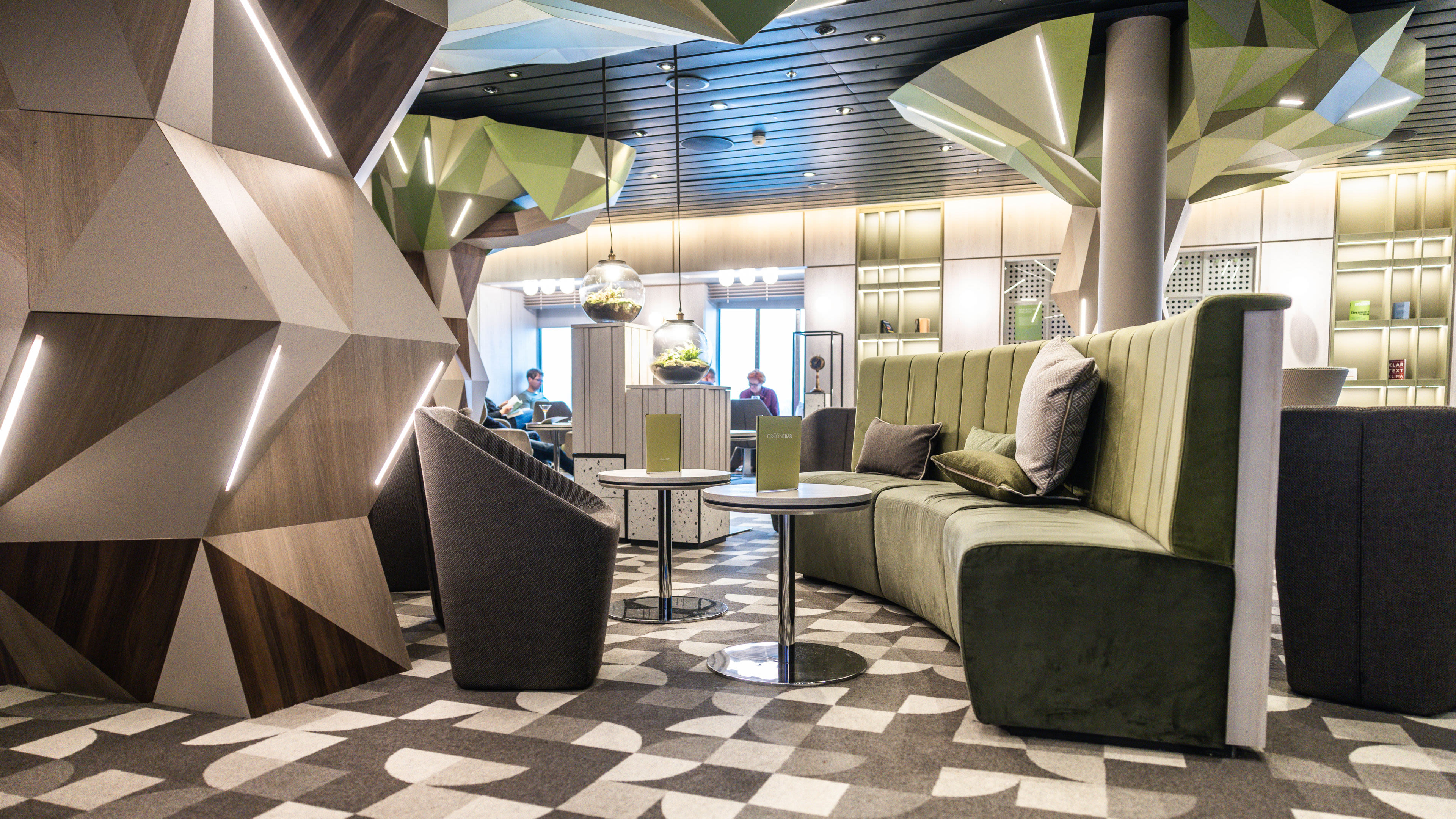 Nachhaltigkeit - Grööne Bar auf der Mein Schiff 3 Moderne Lounge mit grünen Sofas, geometrischen Wänden und hängenden Pflanzen.