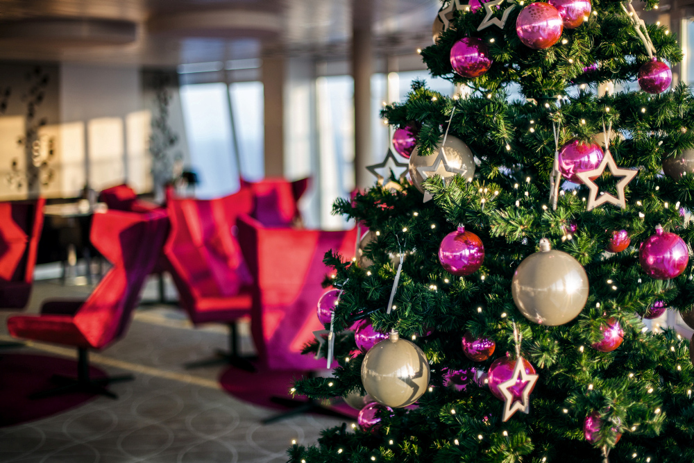 Weihnachtsbaum mit rosa Kugeln und Sternen, rote Stühle im Hintergrund.