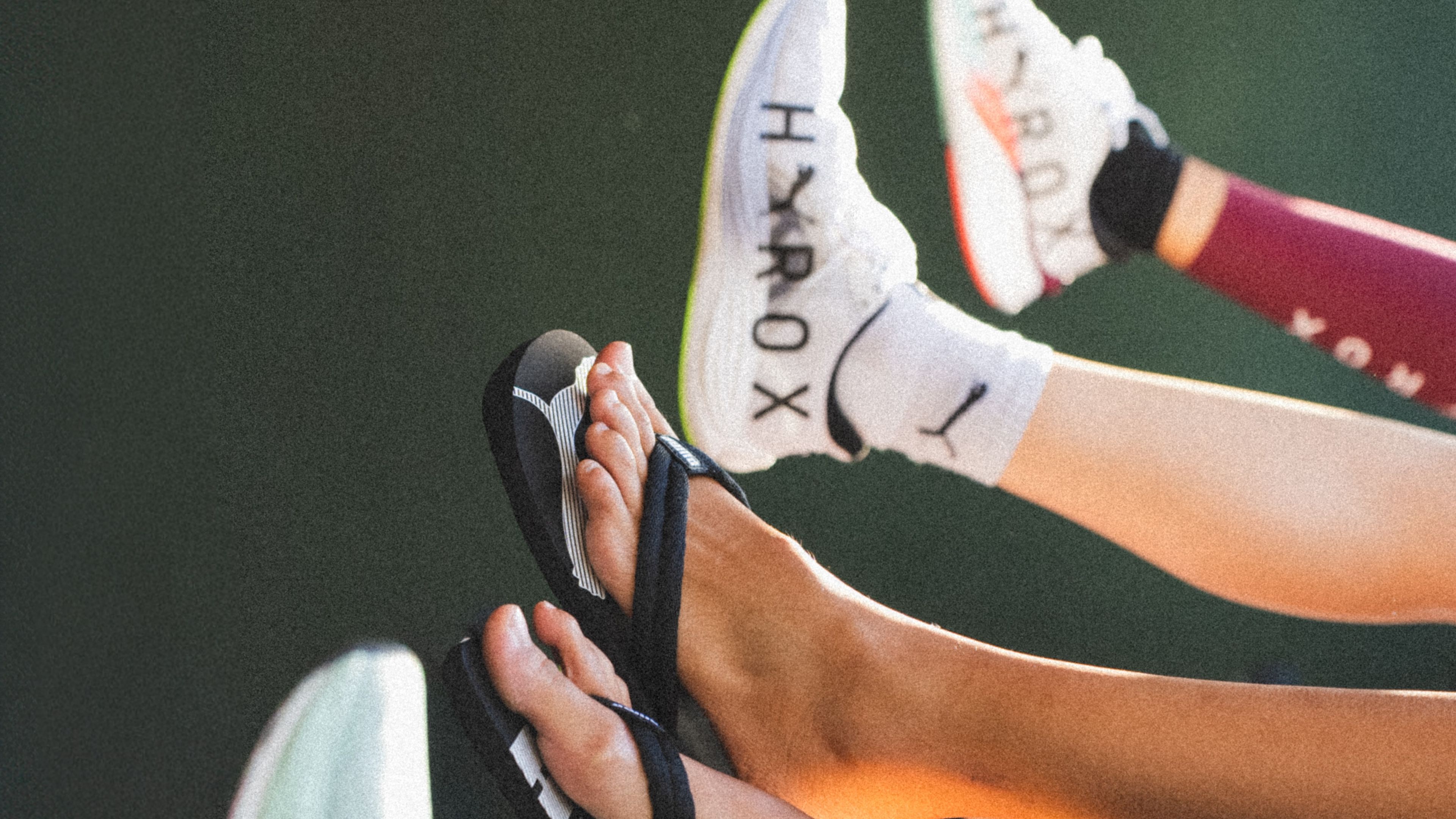 Füße in Flip-Flops und Sportschuhen, grüne Hintergrundfarbe. Füße in Flip-Flops und Sportschuhen, grüne Hintergrundfarbe.