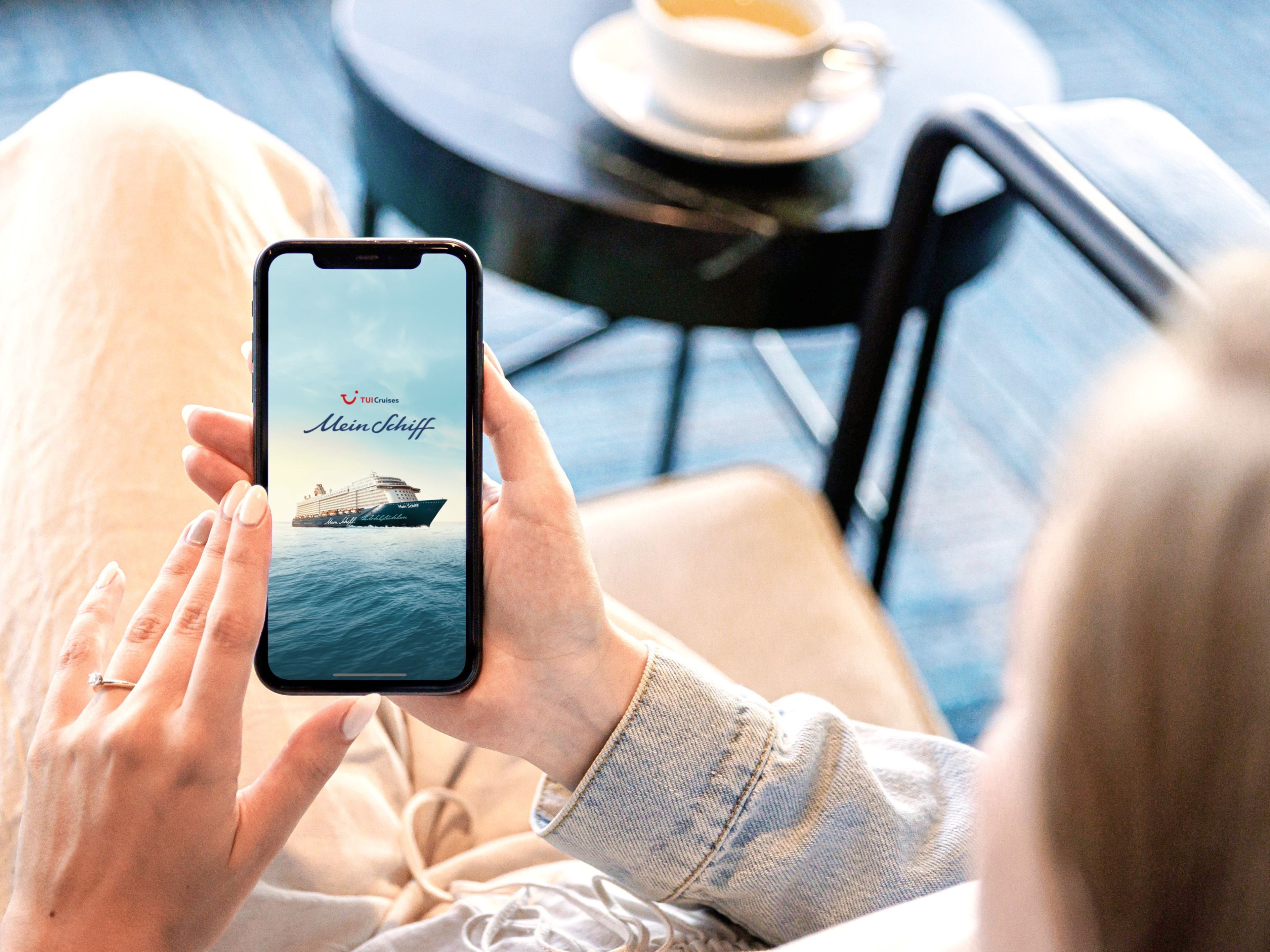 Frau betrachtet Kreuzfahrtschiff der Mein Schiff® Flotte auf Smartphone. Frau betrachtet Kreuzfahrtschiff der Mein Schiff® Flotte auf Smartphone.