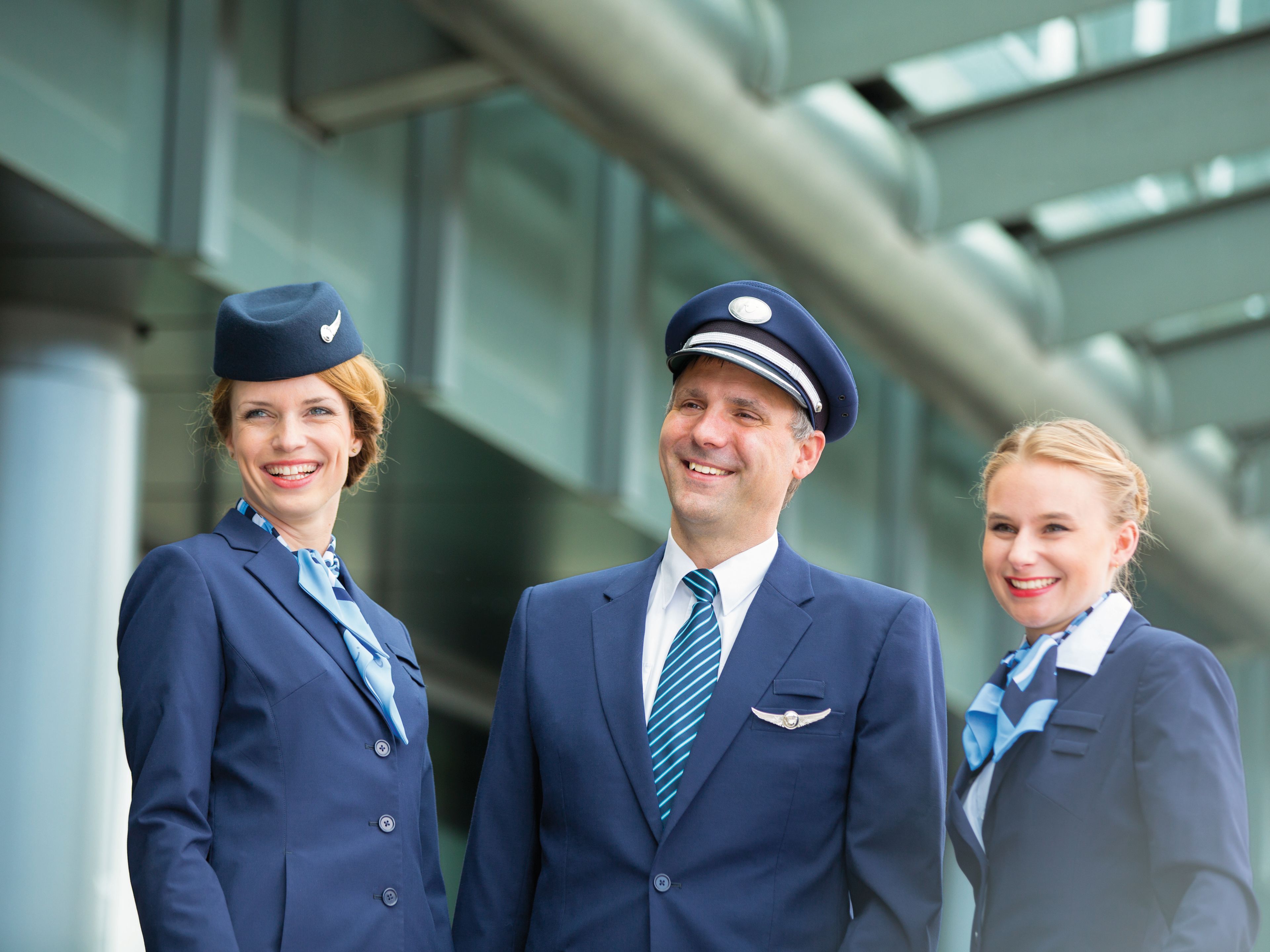 Flugbegleiter und Pilot in blauen Uniformen lächeln. Flugbegleiter und Pilot in blauen Uniformen lächeln.